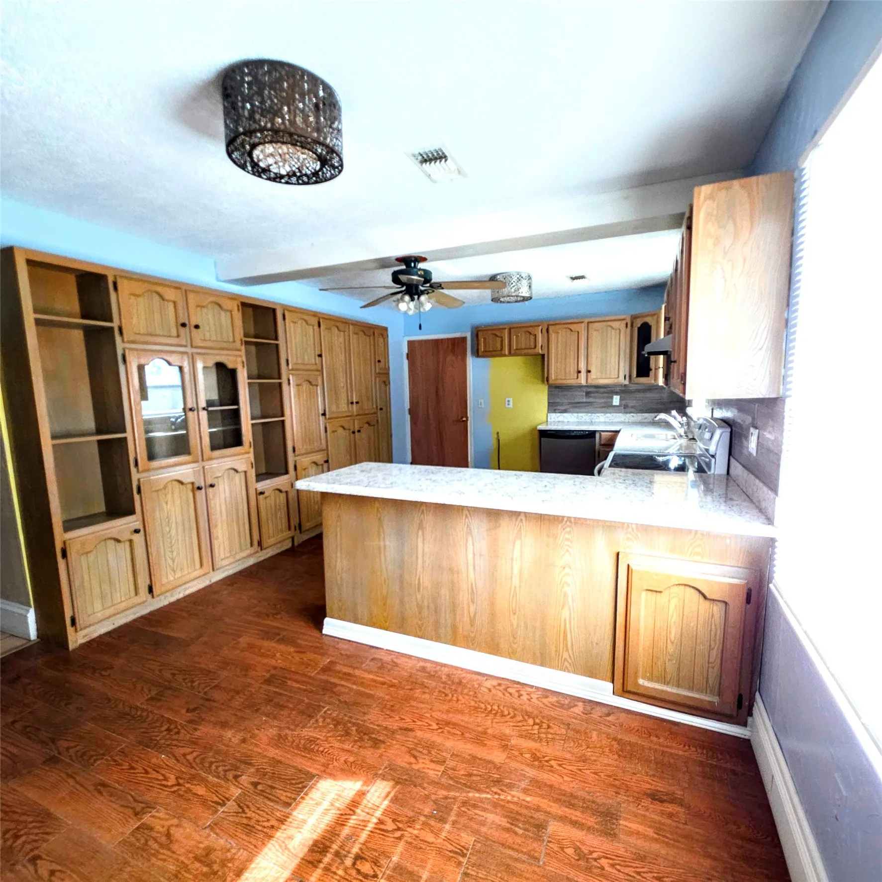 Kitchen with a peninsula, dark wood-style floors, dishwashing machine, and range