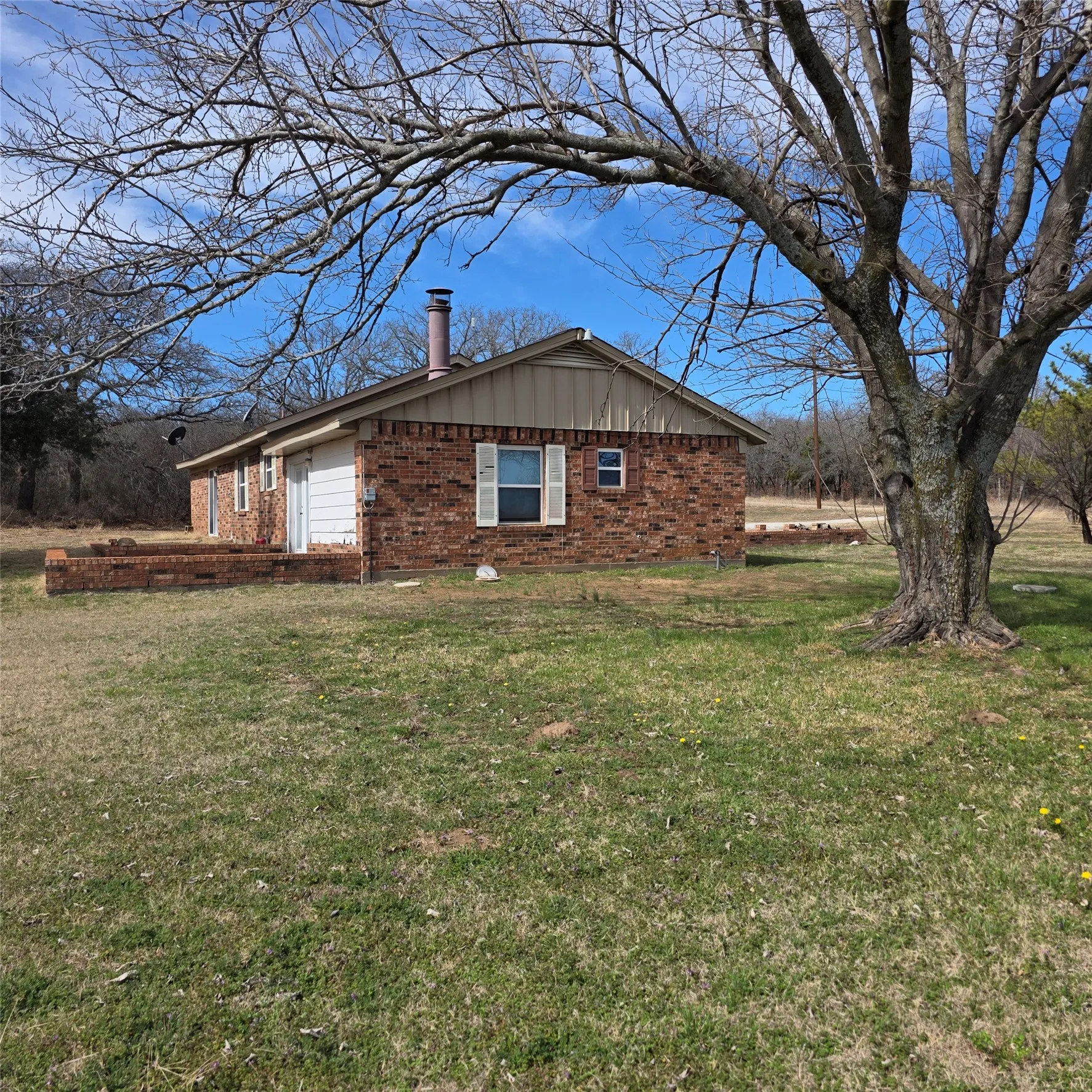 View of side of property featuring brick siding, a chimney, and a lawn