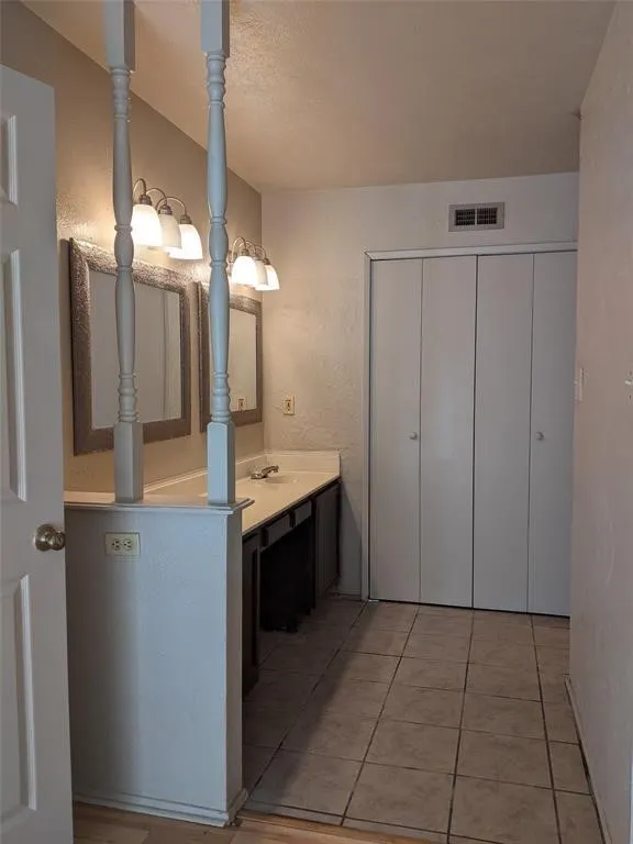 Bathroom with vanity, a textured wall, and light tile patterned floors