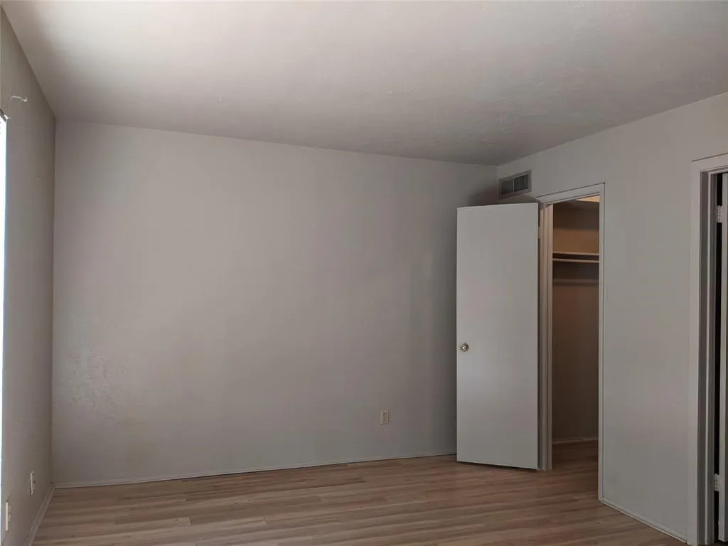 Unfurnished bedroom featuring light wood-style flooring and a spacious closet