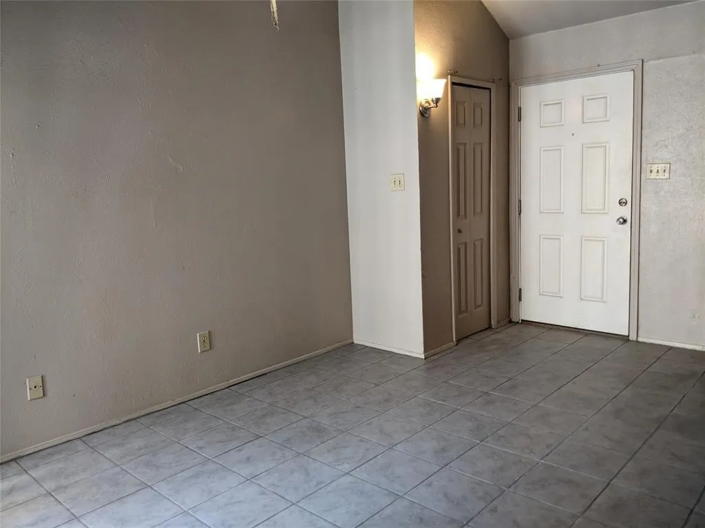 Empty room featuring tile patterned flooring and a textured wall