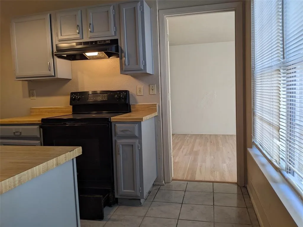 Kitchen featuring black electric range oven, light countertops, gray cabinets, and light tile patterned floors
