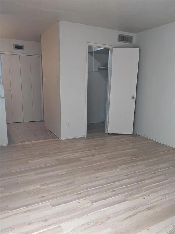 Unfurnished bedroom featuring a walk in closet and light wood-type flooring