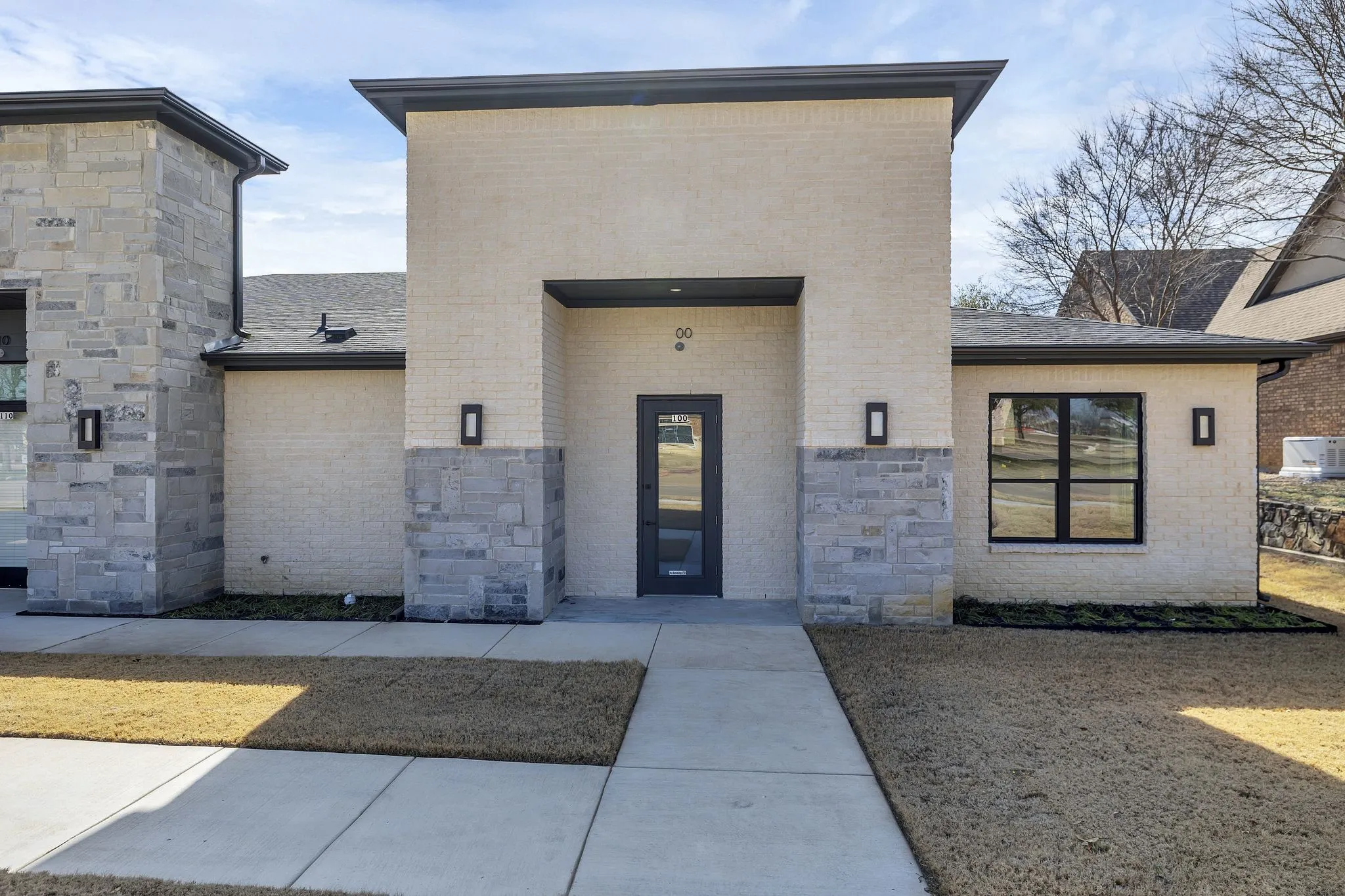 View of exterior entry featuring brick siding, stone siding, and a shingled roof