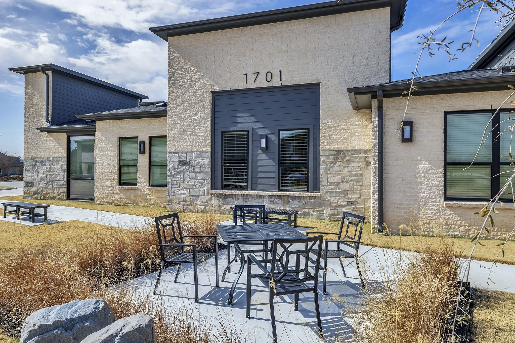 Rear view of house featuring outdoor dining area, a patio, stone siding, and brick siding