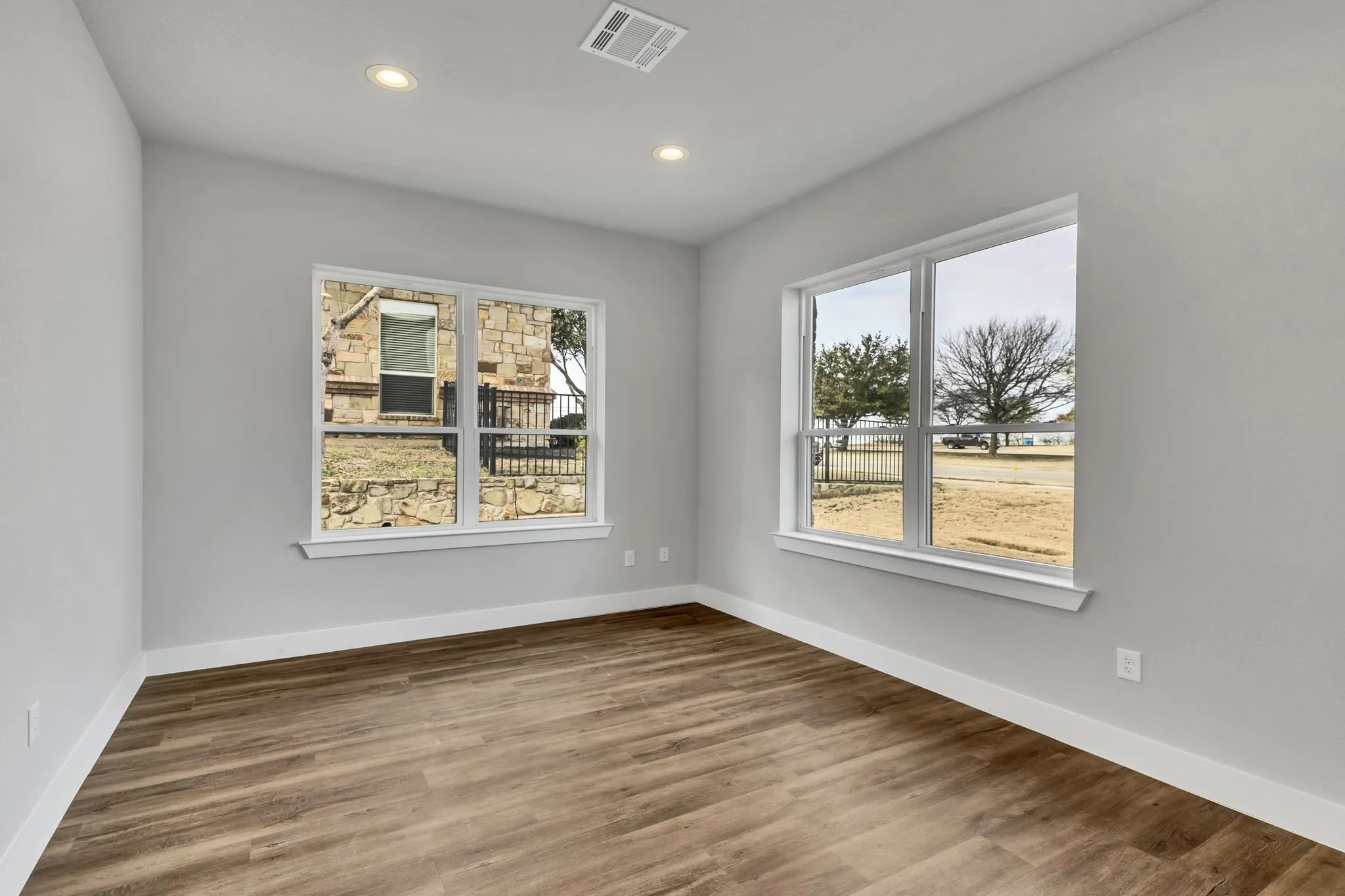 Empty room with dark wood-type flooring and recessed lighting