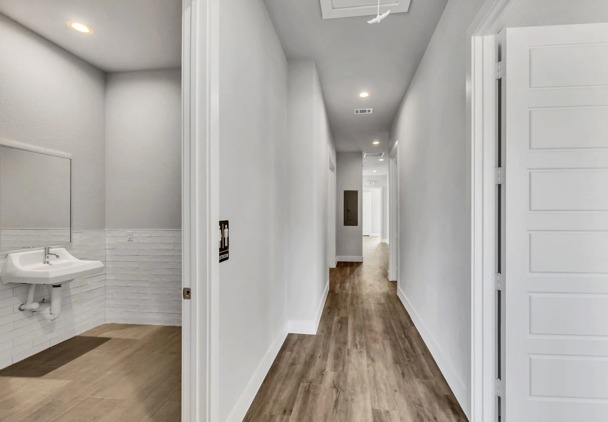 Corridor featuring light wood finished floors, recessed lighting, and tile walls