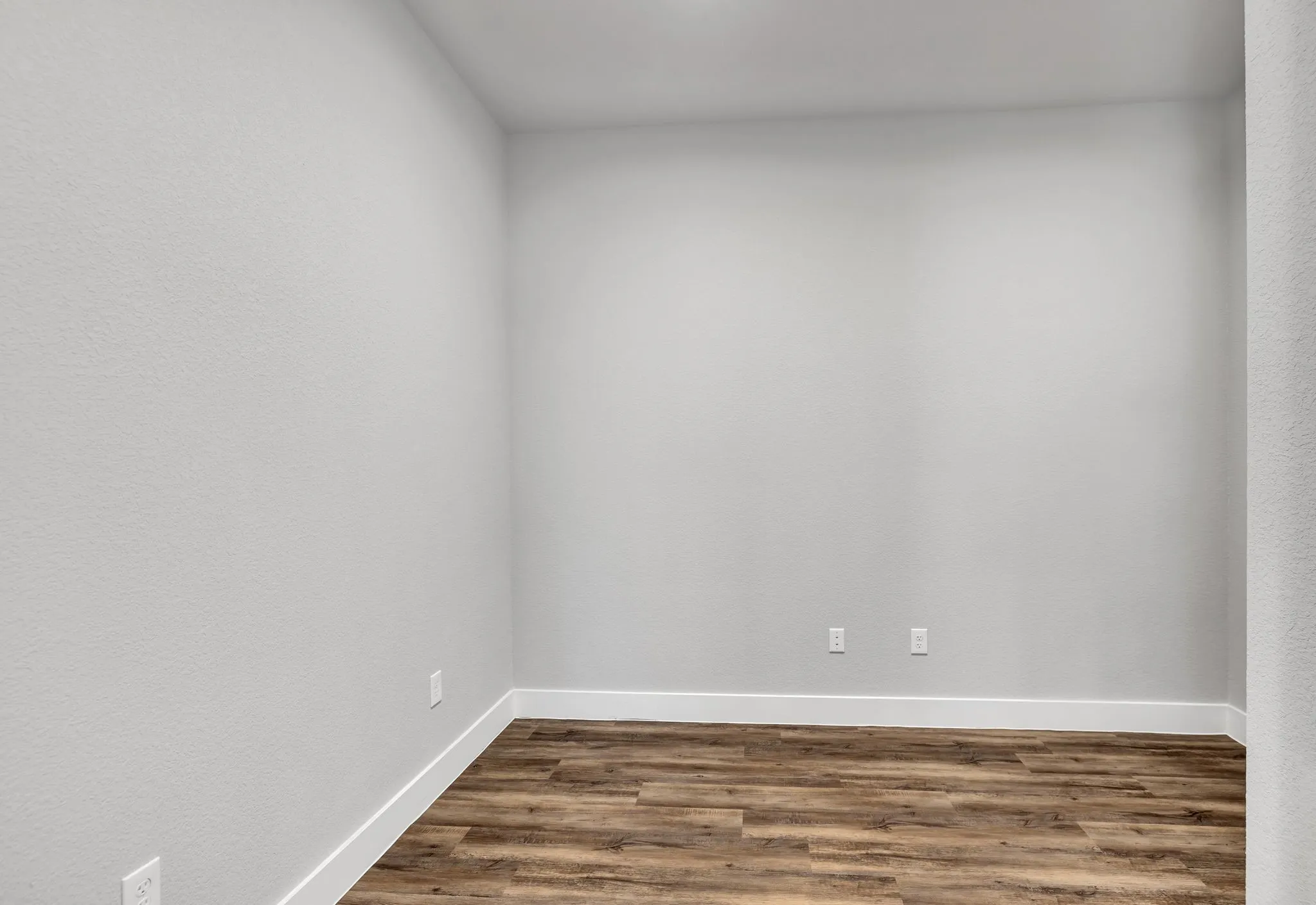 Empty room featuring wood finished floors and a textured wall