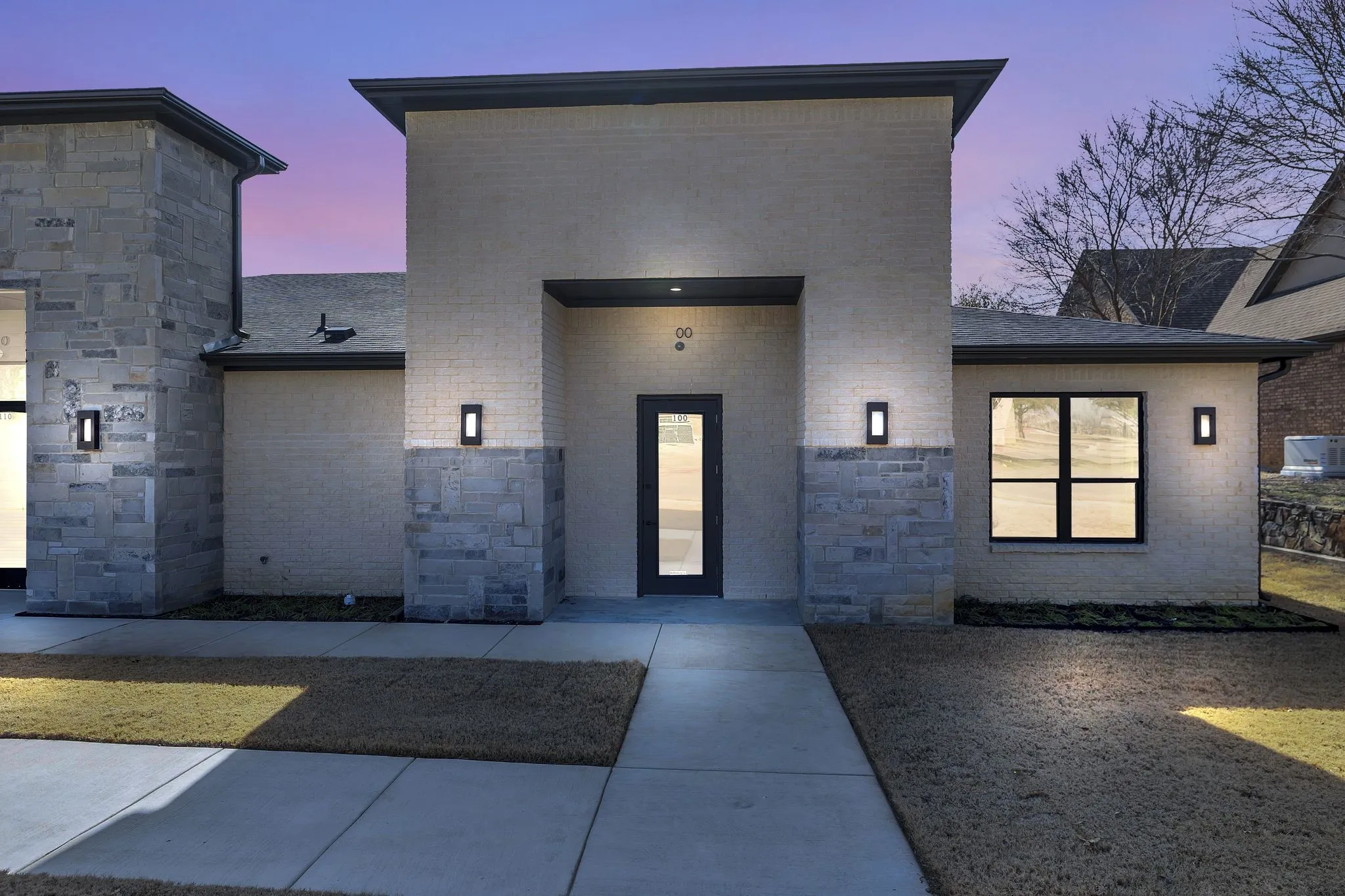 Exterior entry at dusk with stone siding and brick siding