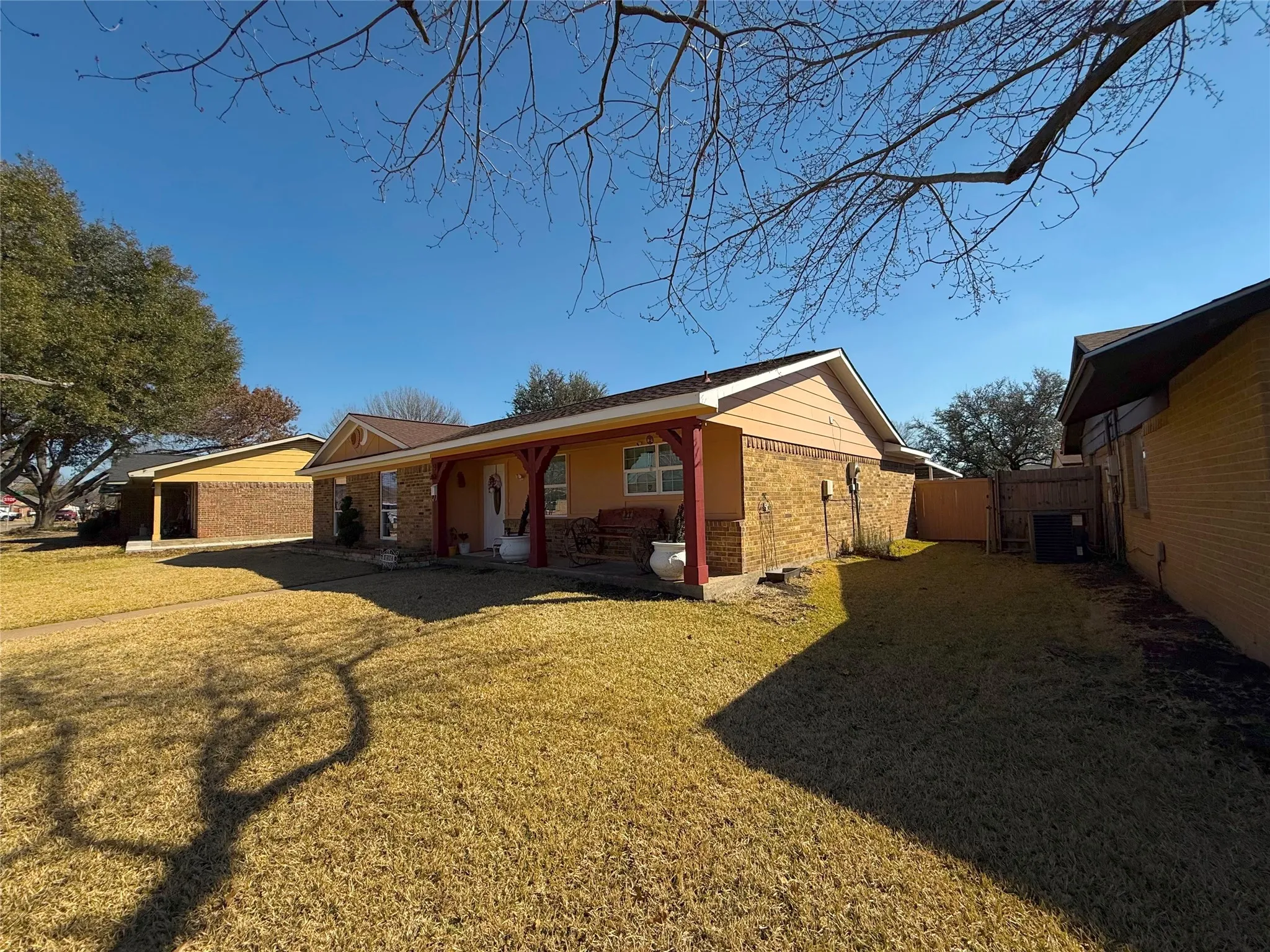 View of home's exterior featuring a lawn, brick siding, and covered porch