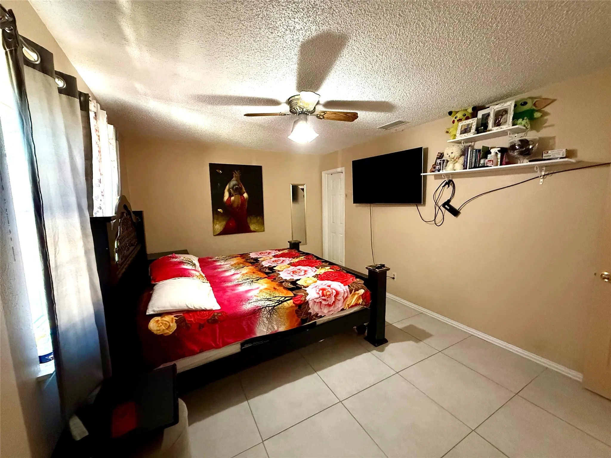 Bedroom with a ceiling fan, a textured ceiling, and light tile patterned flooring
