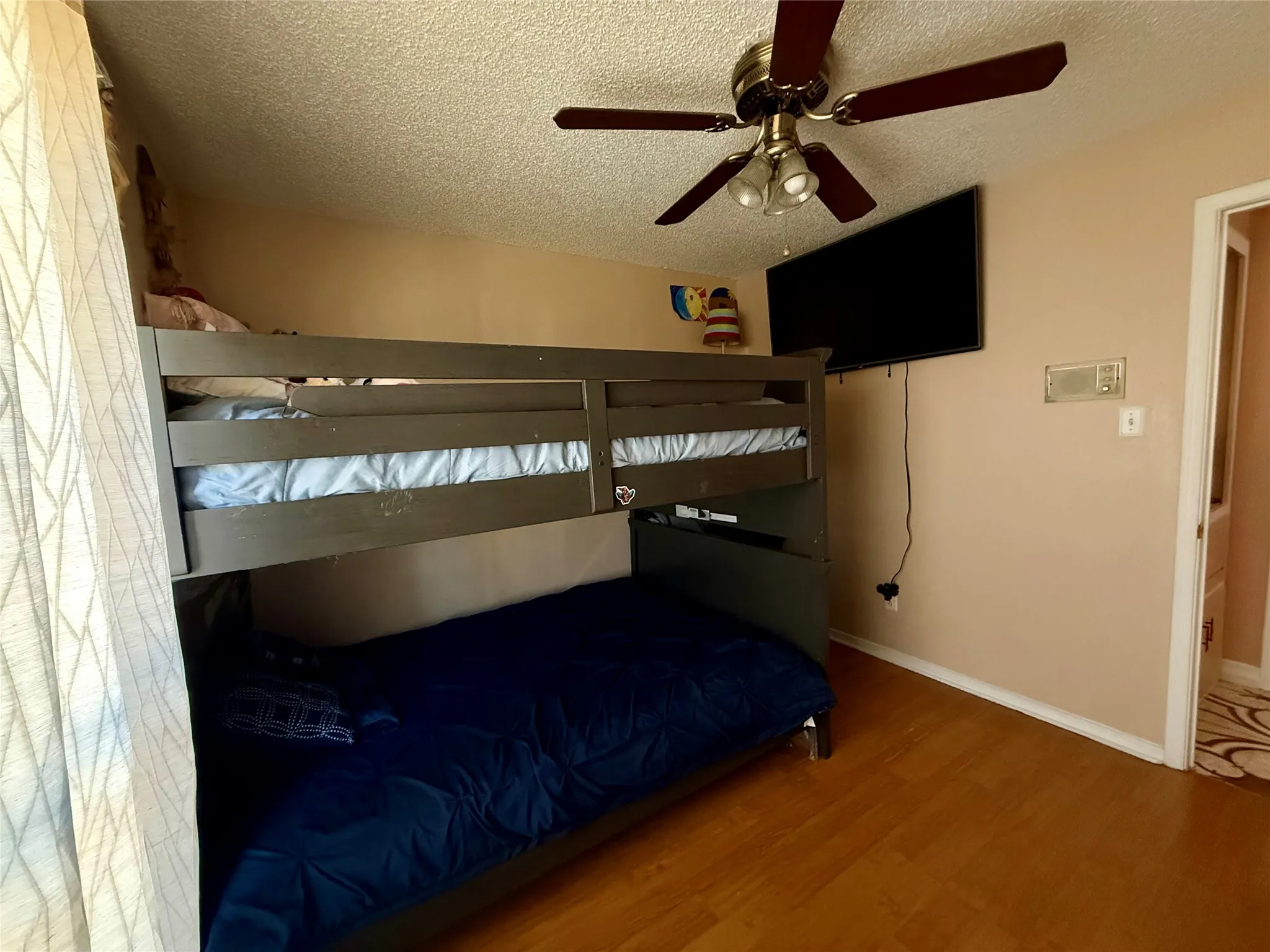 Bedroom with a textured ceiling, wood finished floors, and a ceiling fan