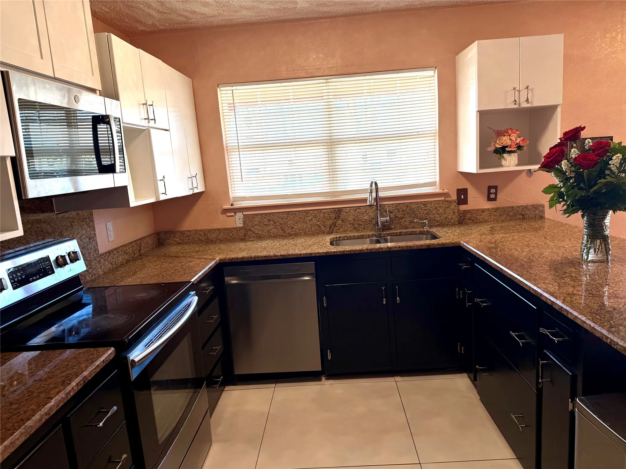 Kitchen featuring stainless steel appliances, light tile patterned floors, and dark stone countertops