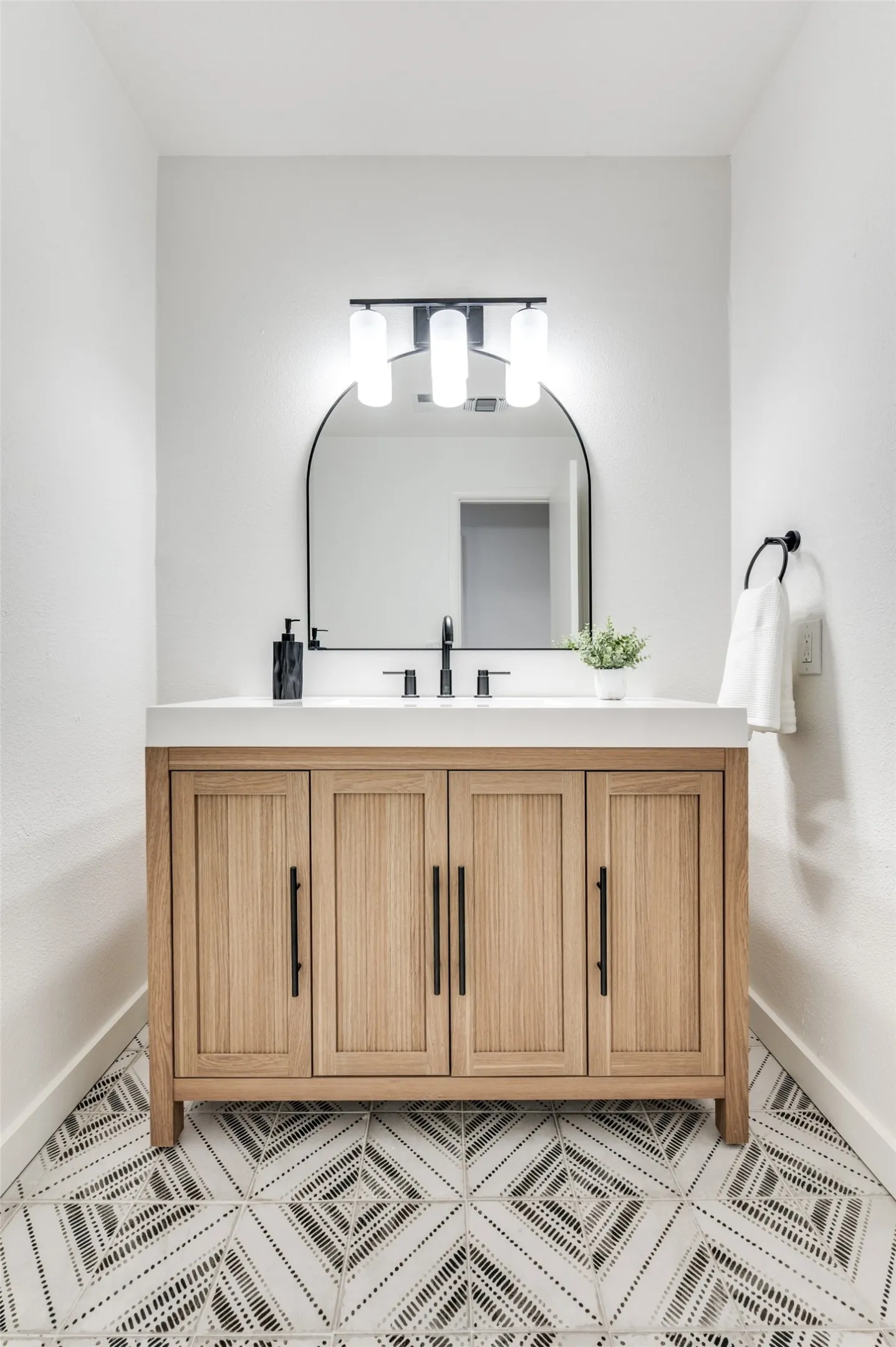 Your guests will love this stylish powder bath featuring modern black fixtures and patterned tile flooring.