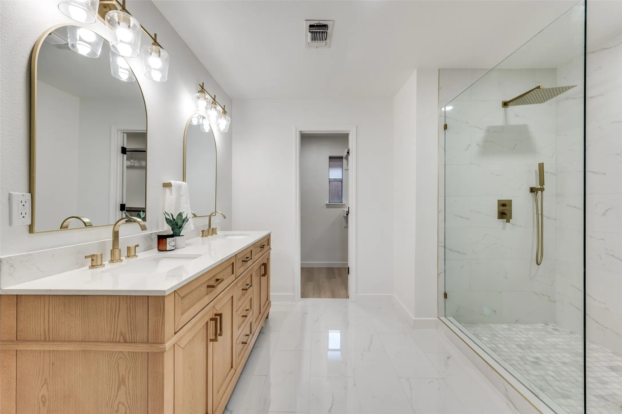 Spa-inspired primary bath featuring dual sinks, marble-topped vanity, and oversized walk-in shower with rainfall head and body sprayer.