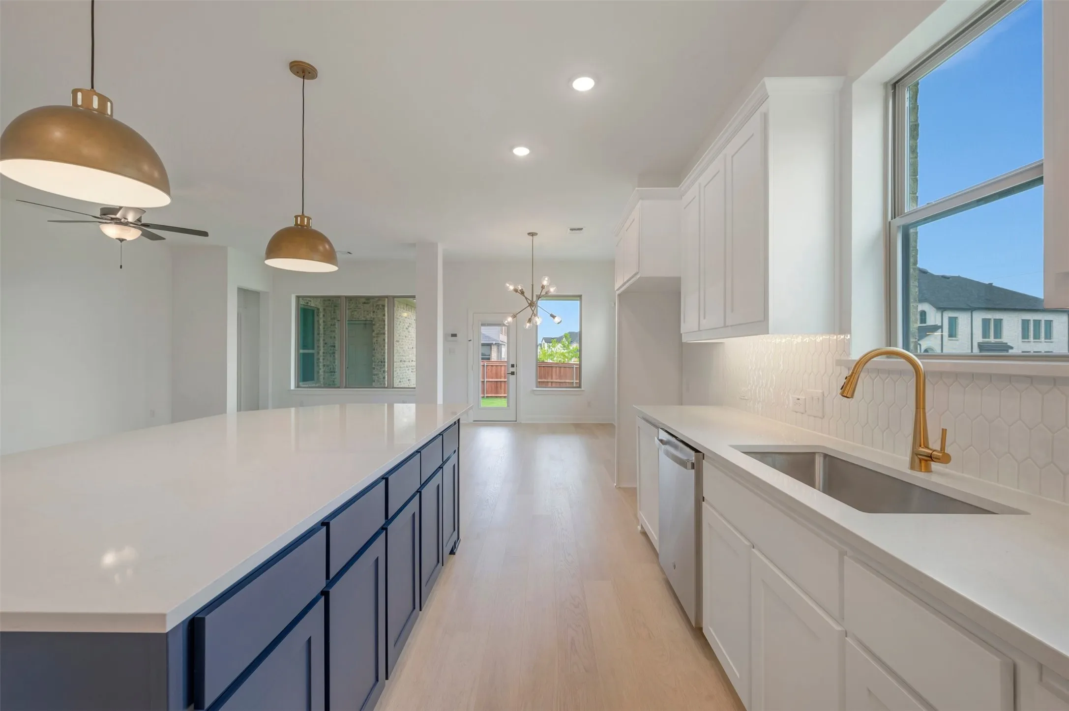 Open-concept kitchen featuring an expansive central island with dark blue cabinetry, recessed lighting, and wood-finish flooring