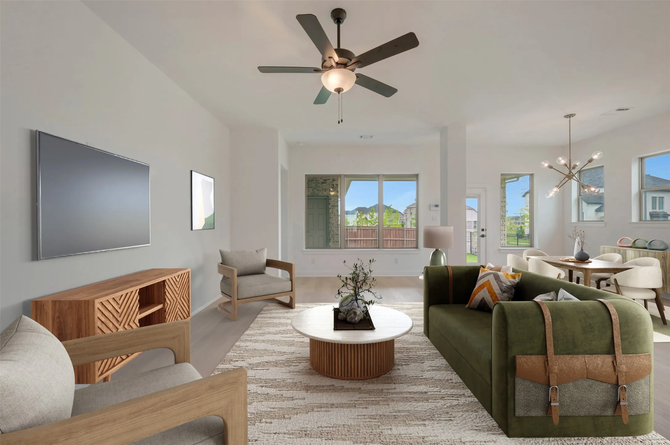 Open-concept living area featuring a ceiling fan, light wood-finish flooring, and ample natural light from multiple windows