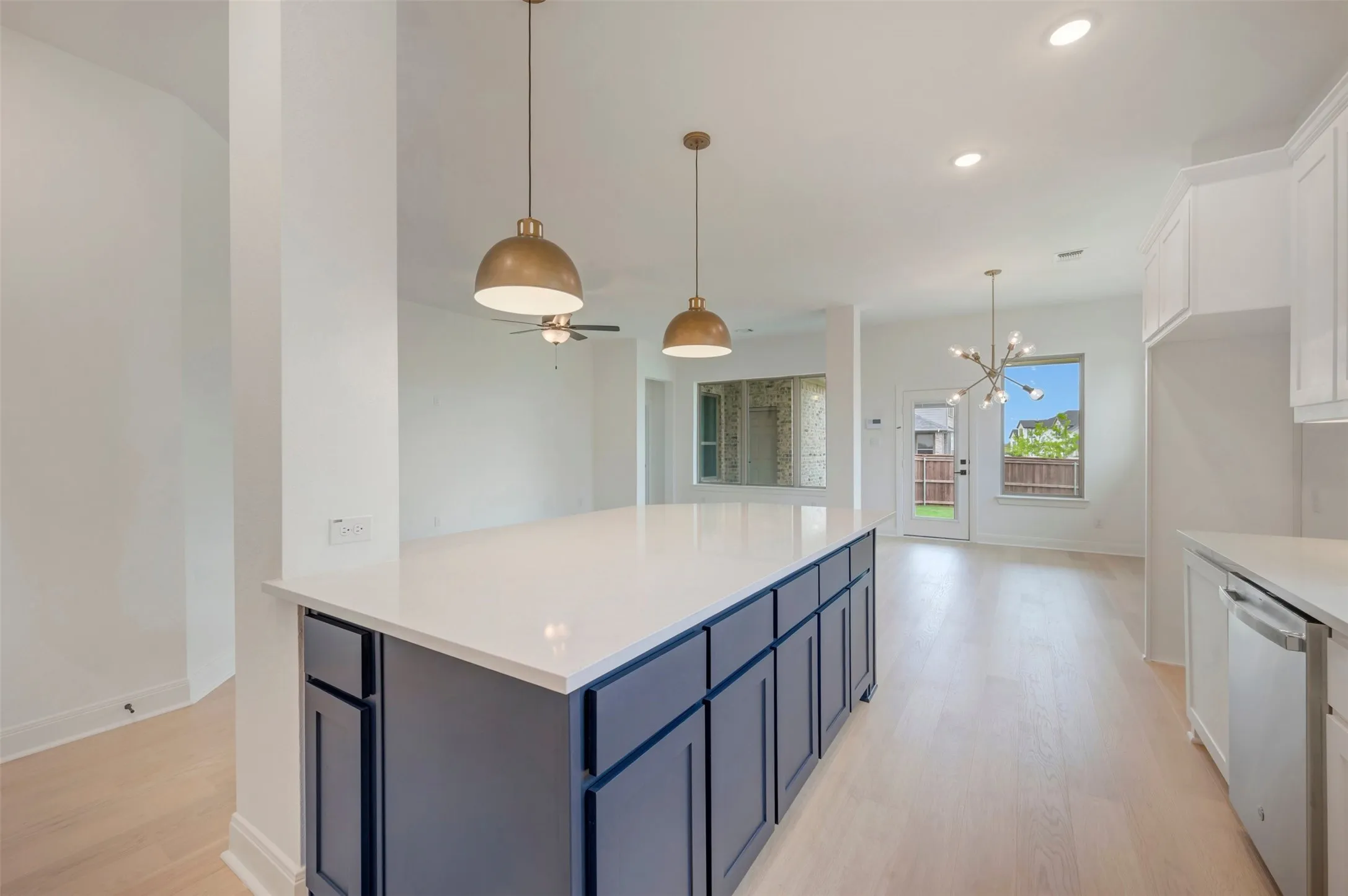 Kitchen island featuring a white countertop and navy cabinetry, complemented by brass pendant lighting