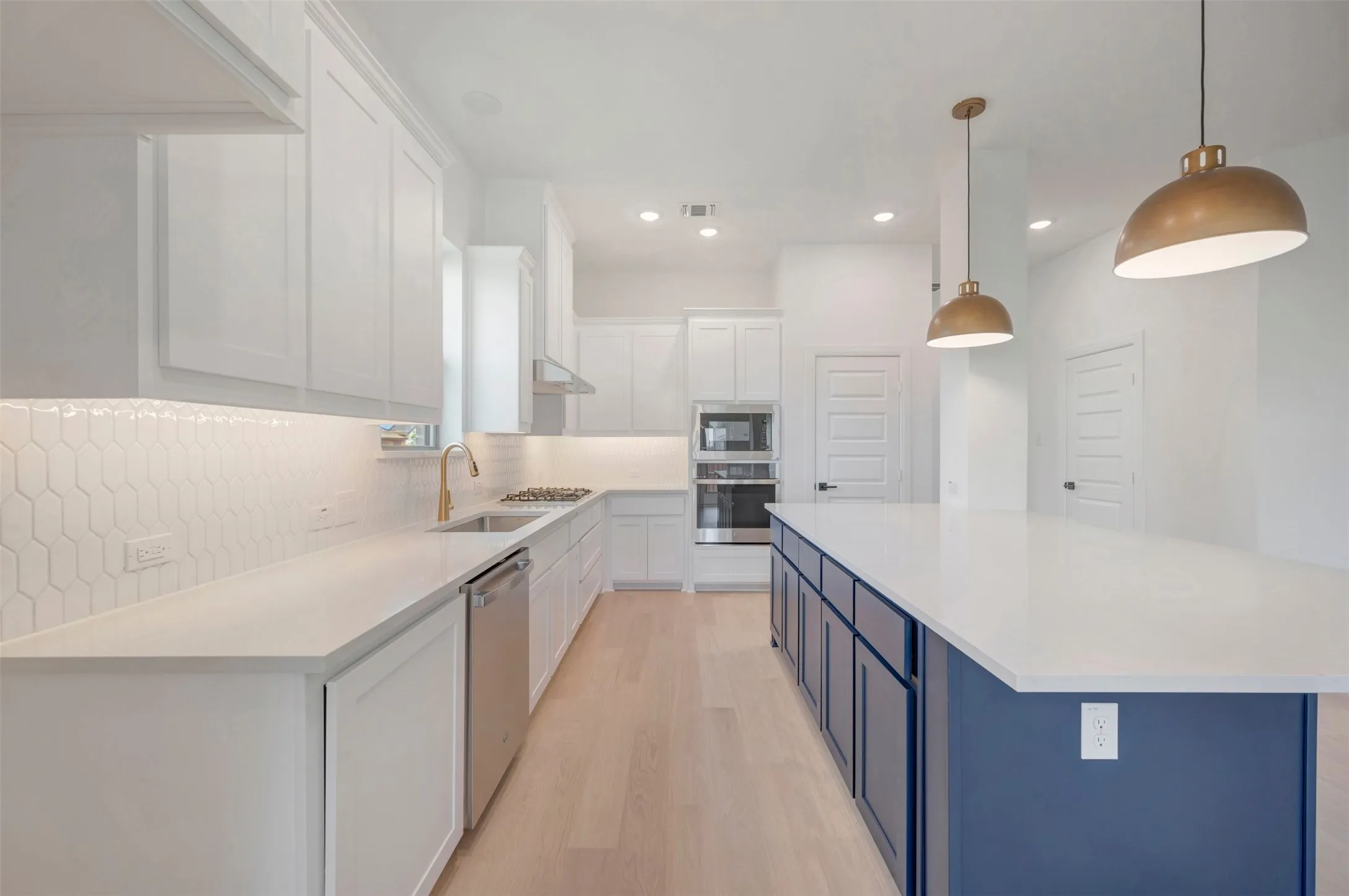 Modern kitchen featuring a large central island with a solid surface countertop and blue cabinetry