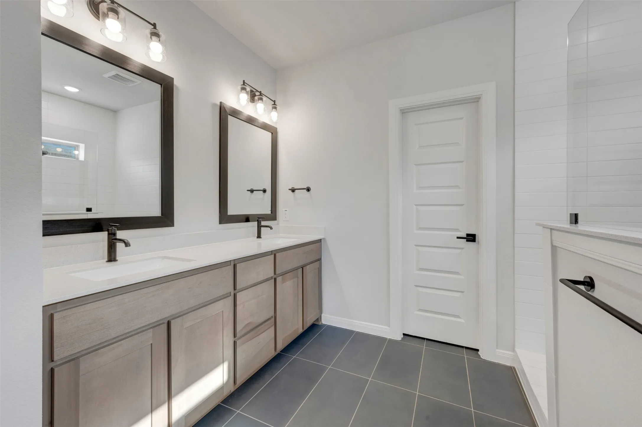 Double vanity with wood-finish cabinetry, white countertops, rectangular undermount sinks, and matte black fixtures