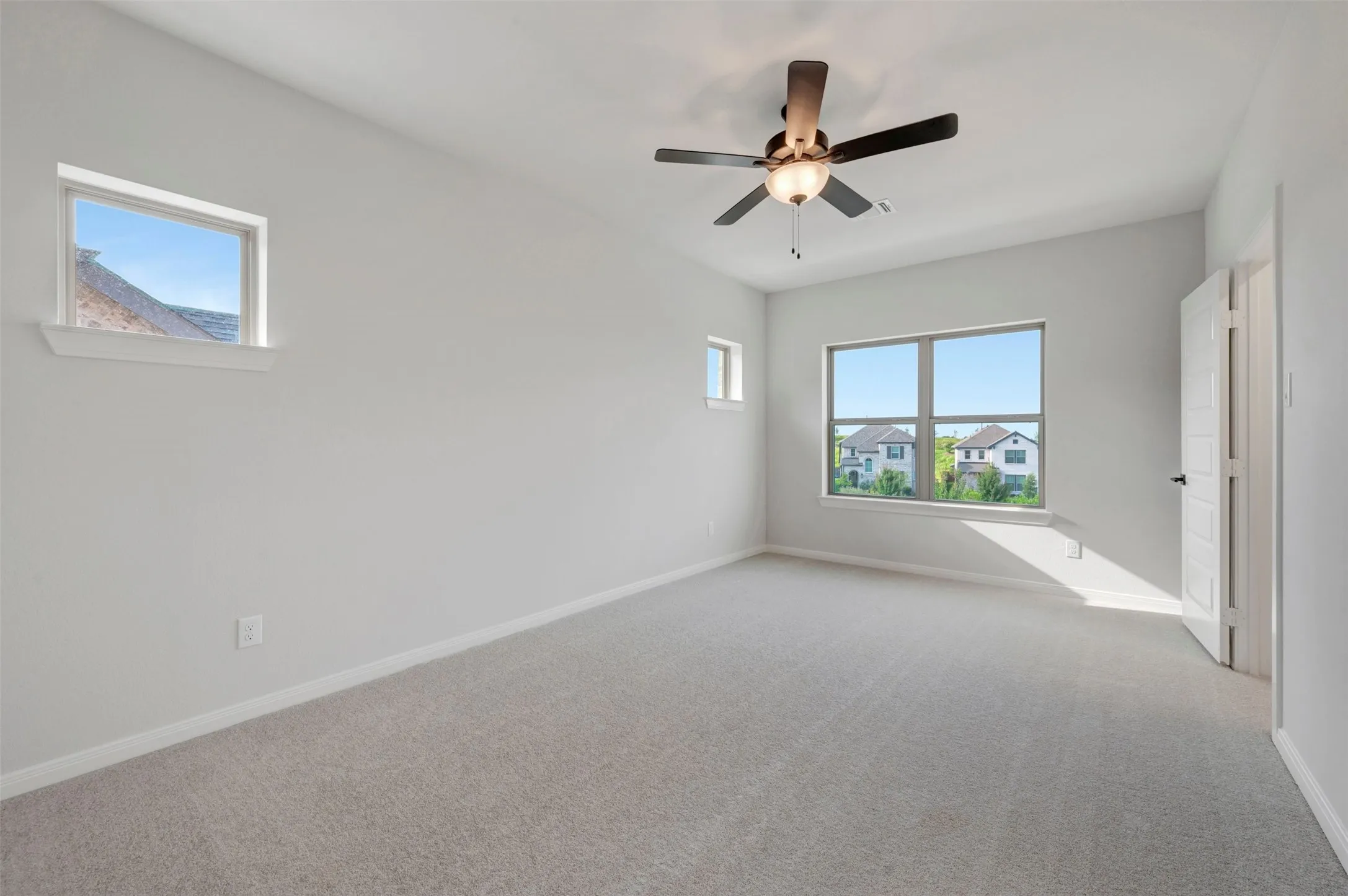Spacious room featuring light gray carpeting and neutral wall paint