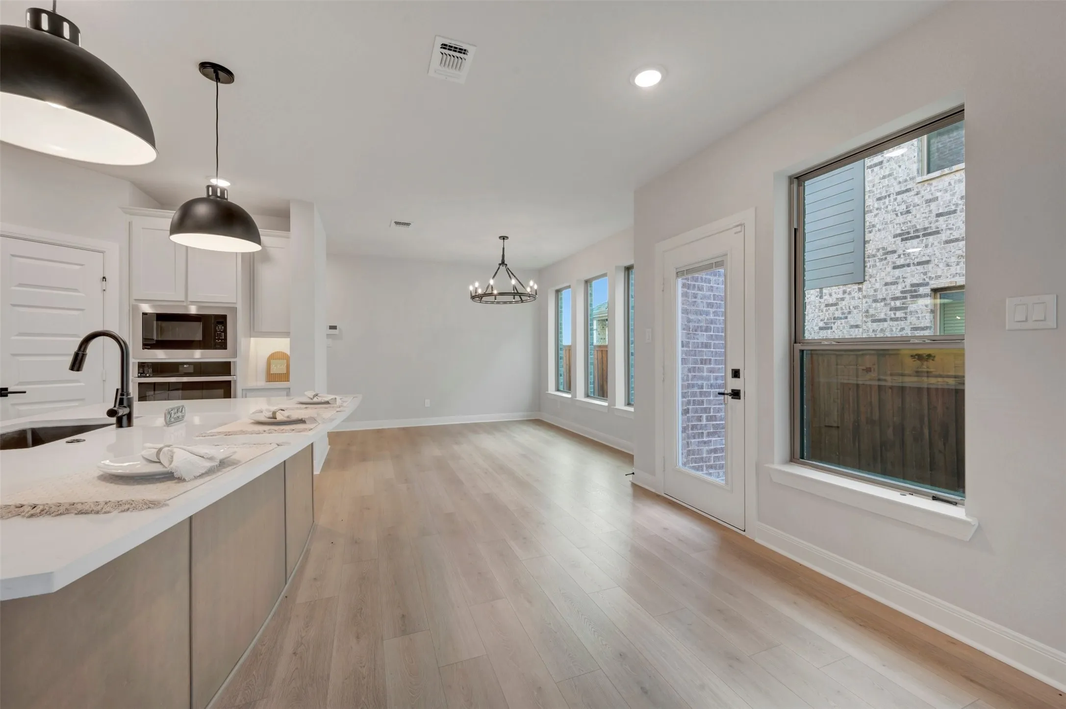 Kitchen island with light-toned cabinetry, a white countertop, and a matte black faucet
