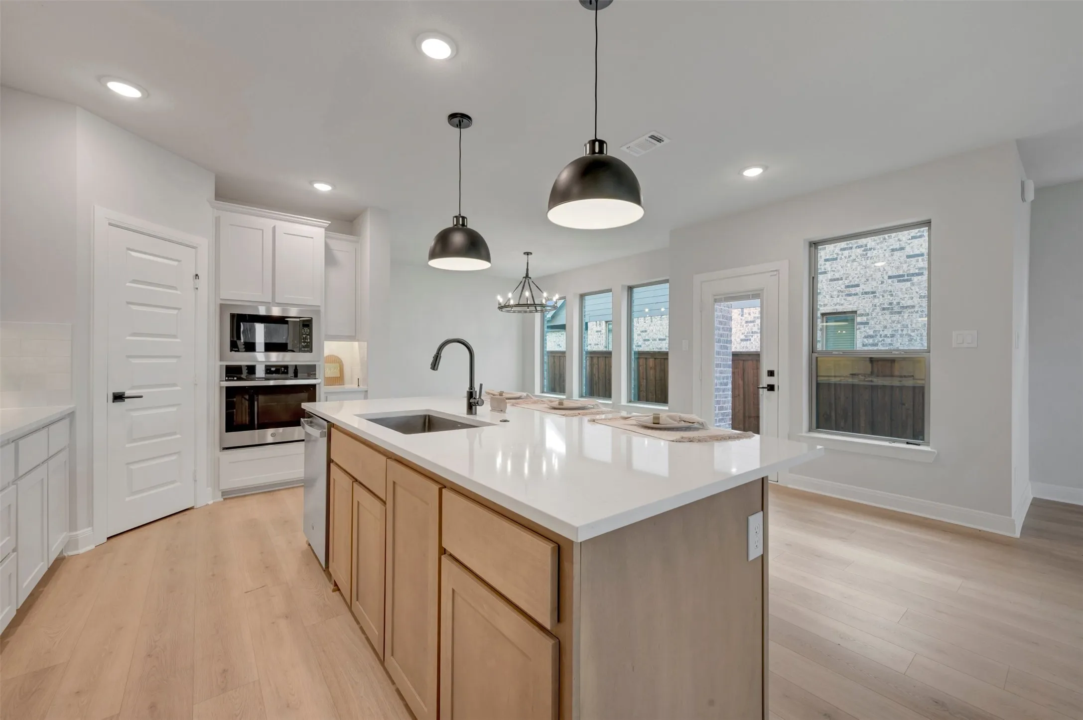 Kitchen featuring a light wood-finish flooring, a central island with a white countertop and natural wood cabinetry, and recessed lighting