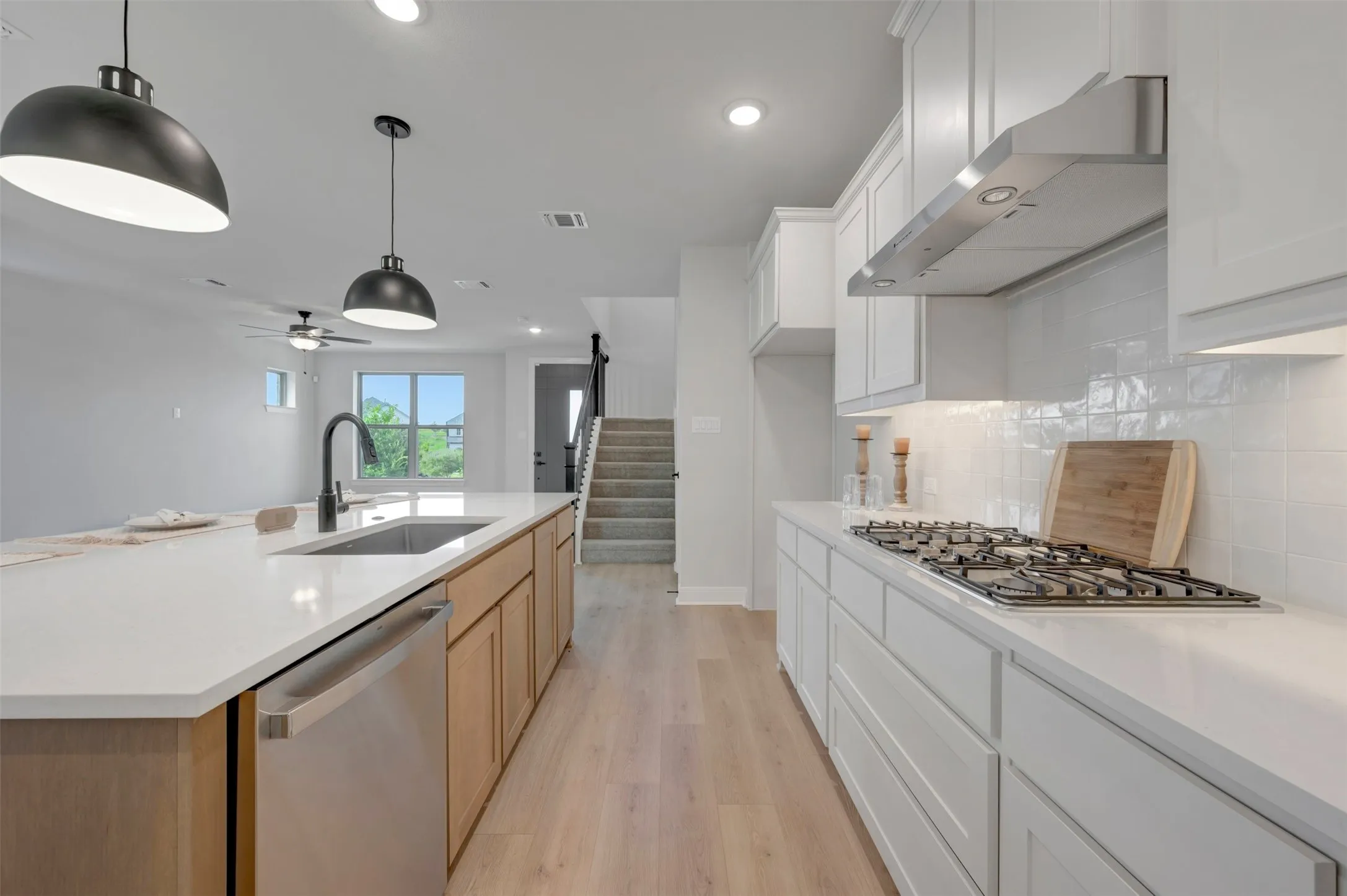 Kitchen featuring a white tile backsplash, stainless steel gas range, and white cabinetry
