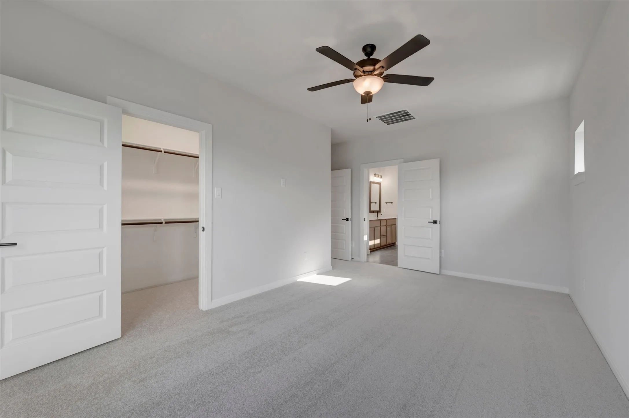 Spacious interior room featuring light gray carpet flooring and white walls