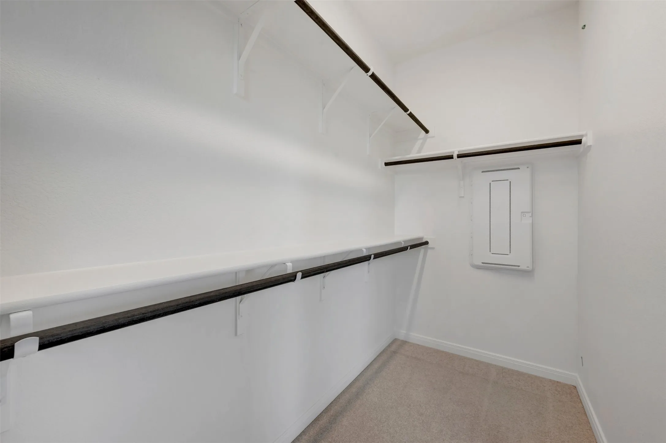Walk-in closet featuring white walls, multi-level shelving, integrated hanging rods, and carpet flooring