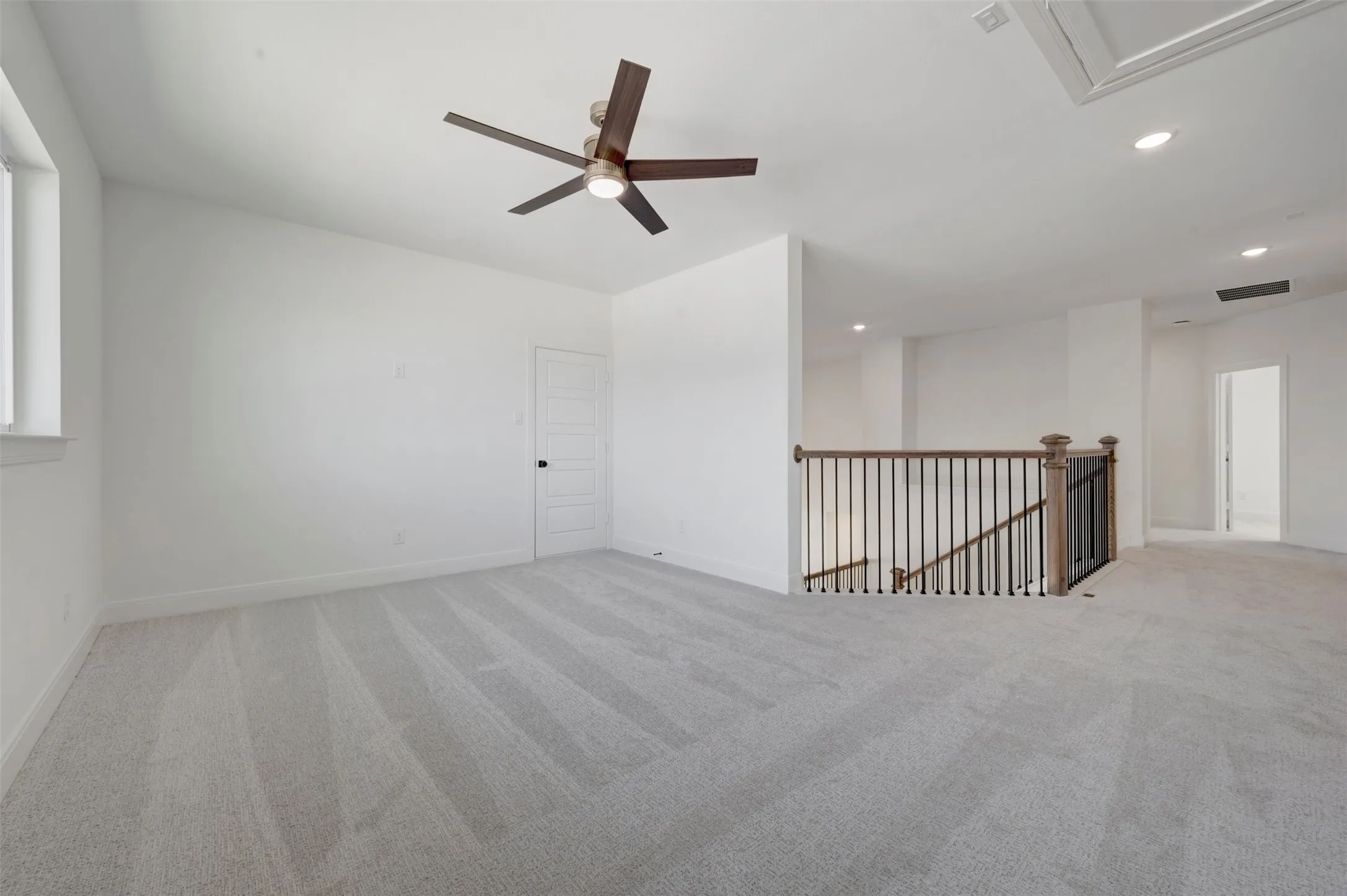 Spacious carpeted room featuring a ceiling fan with integrated lighting, recessed lighting, and a window for natural light