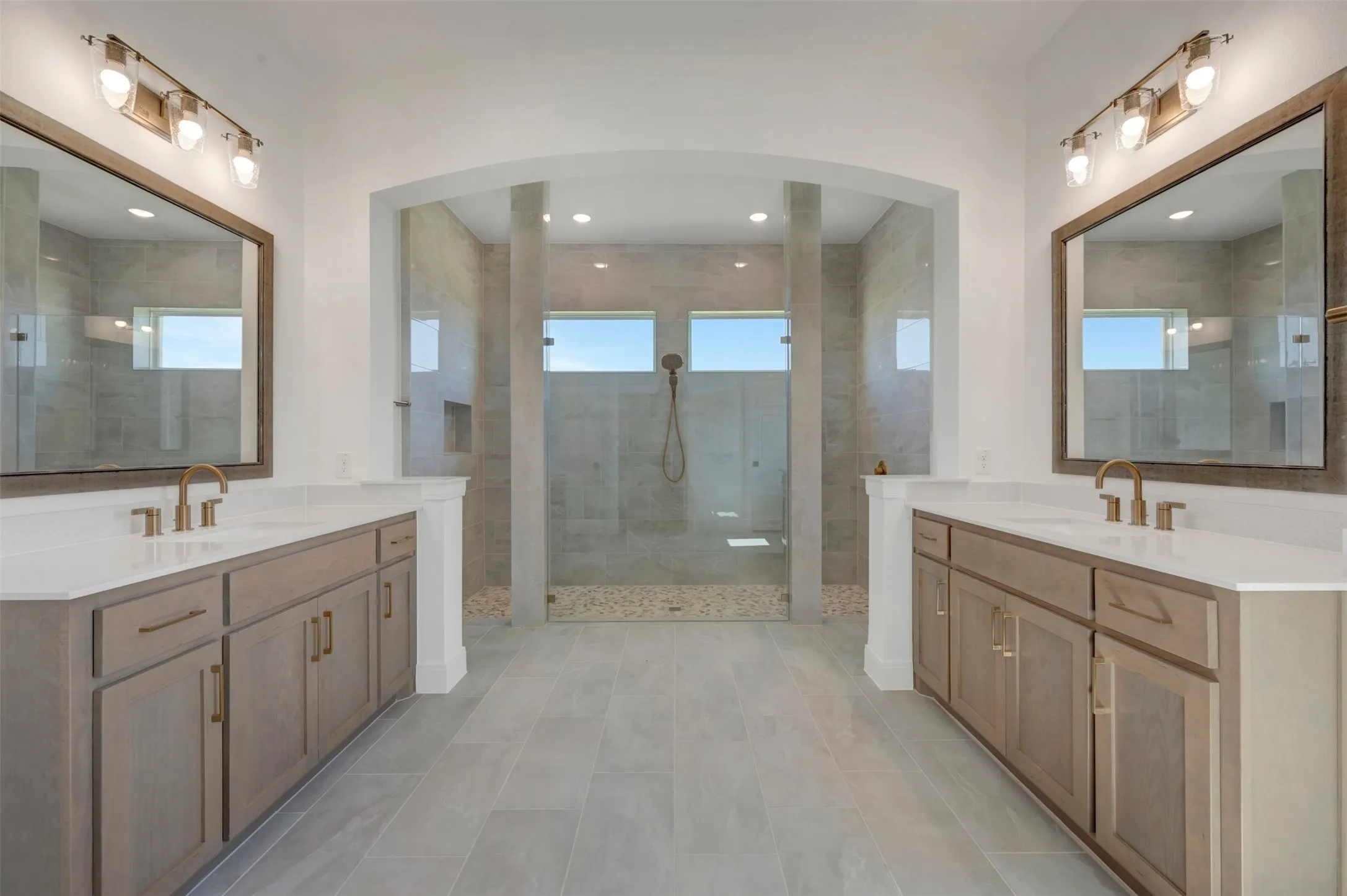 Spacious bathroom featuring a large walk-through shower with dual entries, pebble flooring, and horizontal windows