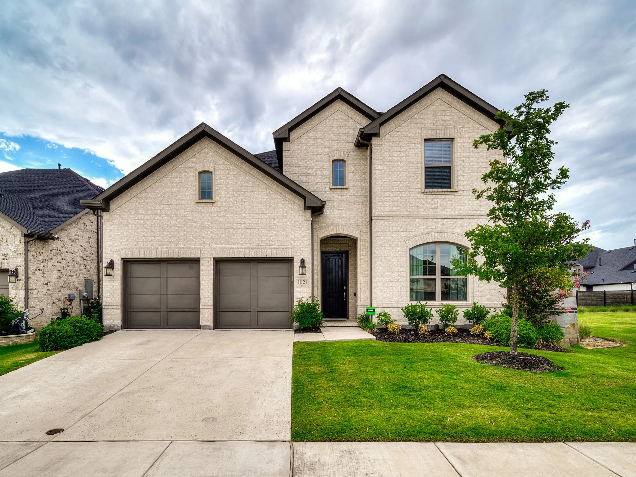 French country inspired facade featuring a front yard, concrete driveway, and brick siding