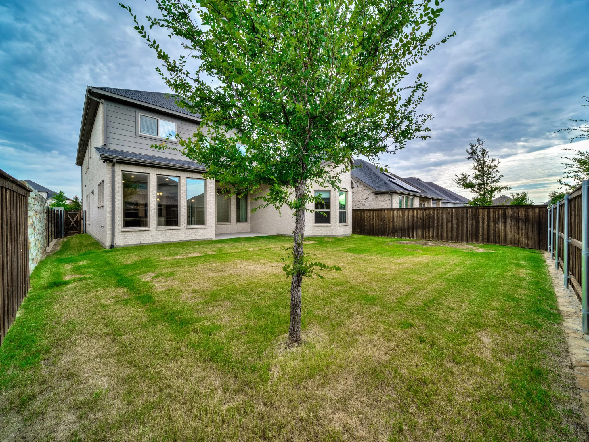 Rear view of house featuring brick siding and a fenced backyard