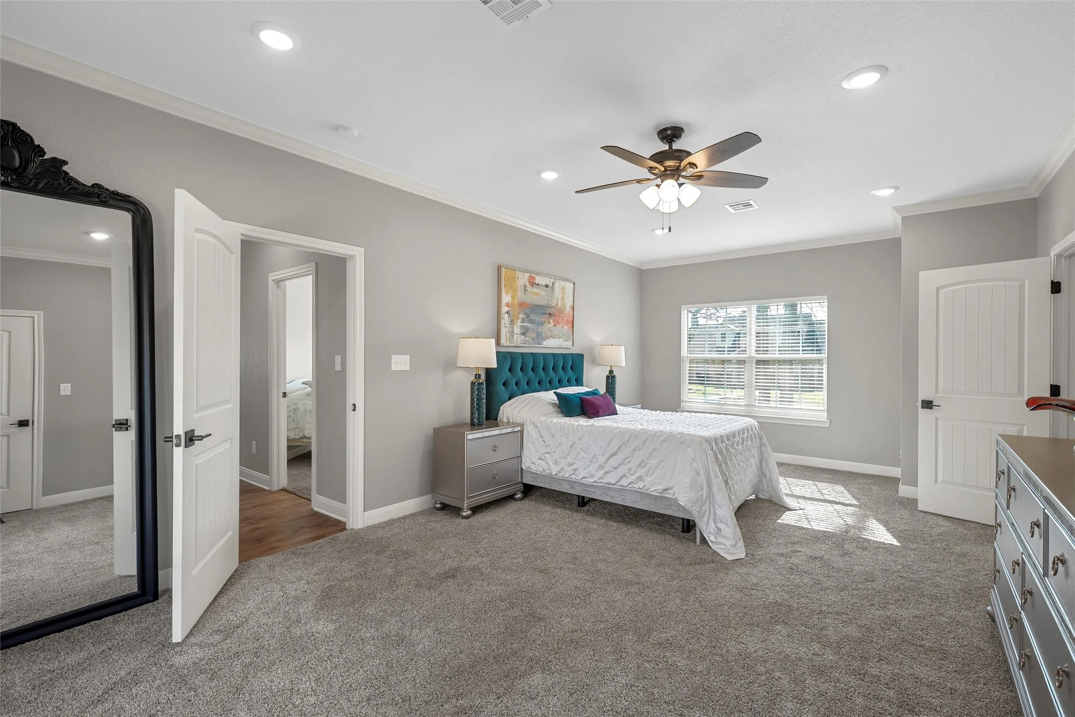 Expansive primary bedroom with plush carpet, crown molding, recessed lighting, ceiling fan, and French doors opening directly to the covered back patio — a private retreat at 117 Lost Oaks Drive, Waco TX 76705.