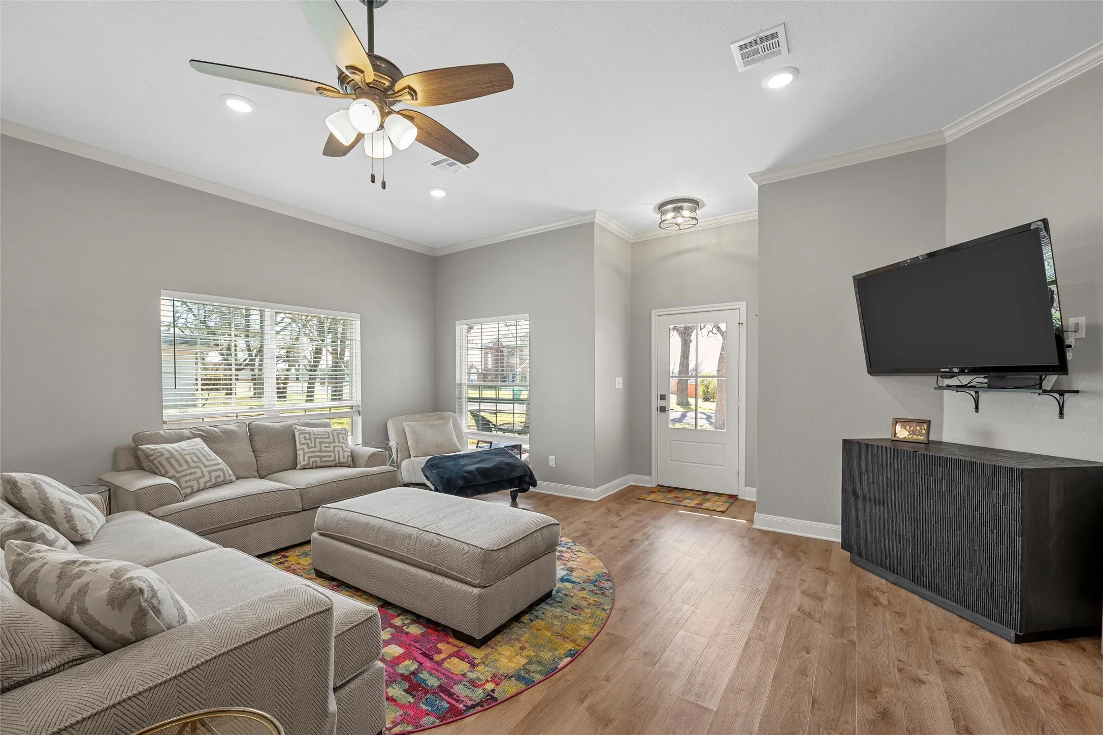 Open-concept living room with crown molding, recessed lighting, ceiling fan, and wood-look luxury vinyl plank floors that flow seamlessly into the kitchen — perfect for entertaining at 117 Lost Oaks Drive, Waco TX.