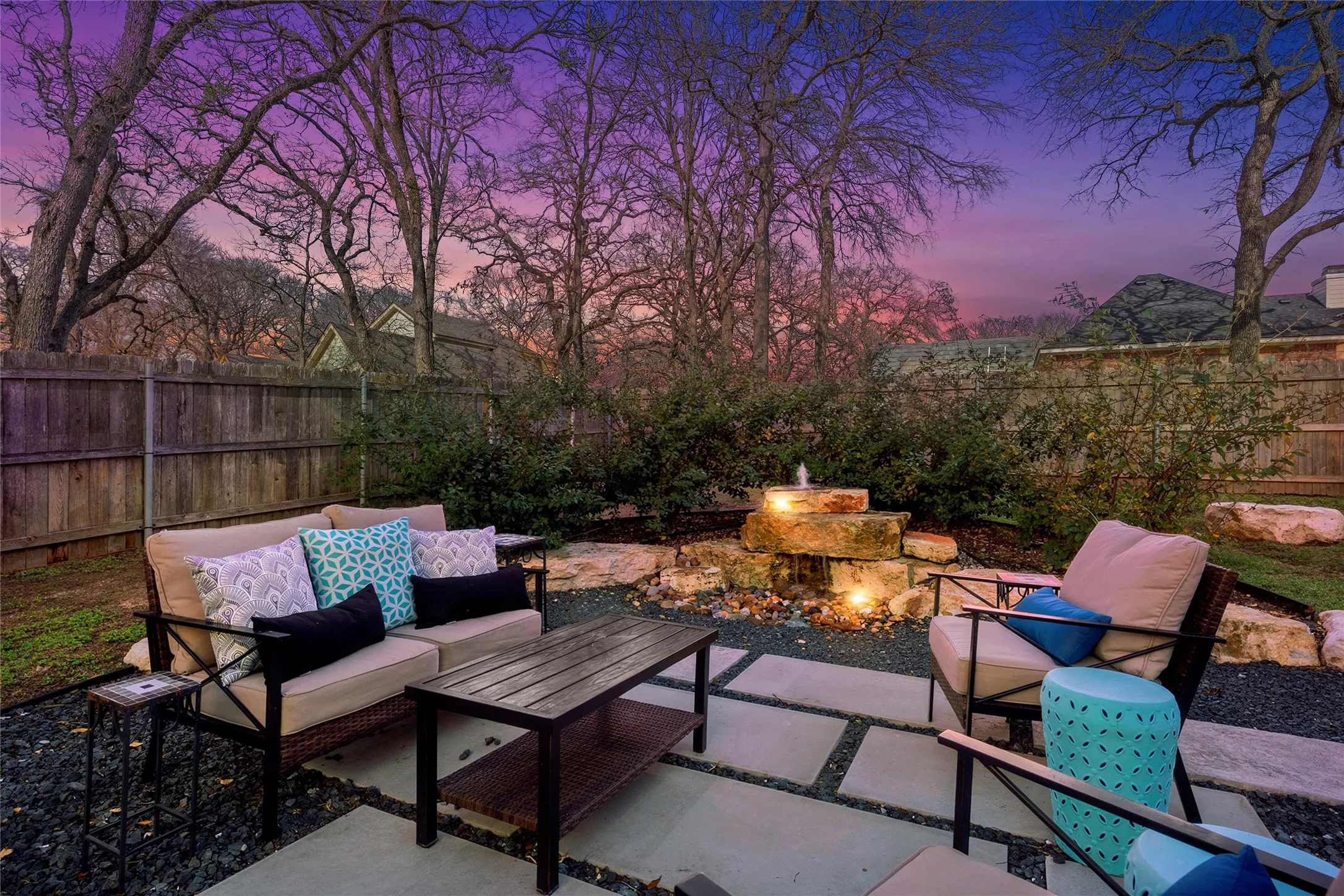 Private backyard retreat with expanded concrete patio, outdoor seating area, natural limestone water fountain feature, mature shade trees, and full wood privacy fence — outdoor living at its best at 117 Lost Oaks Drive, Waco TX 76705.