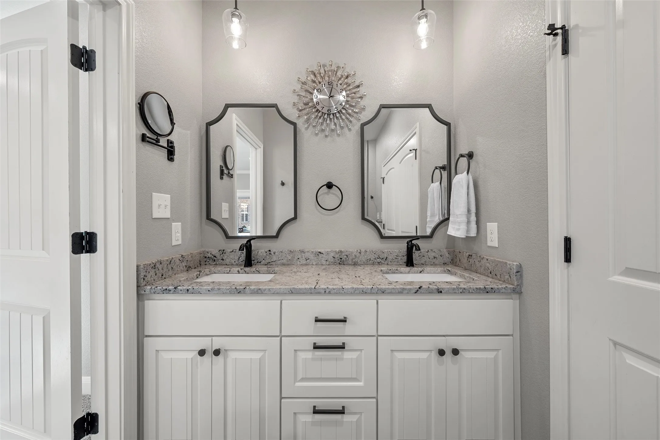 Spa-style primary bathroom with double-sink granite vanity, custom white cabinetry, black matte hardware, dual pendant lighting, separate shower, and private soaking tub — 117 Lost Oaks Drive, Waco TX 76705.