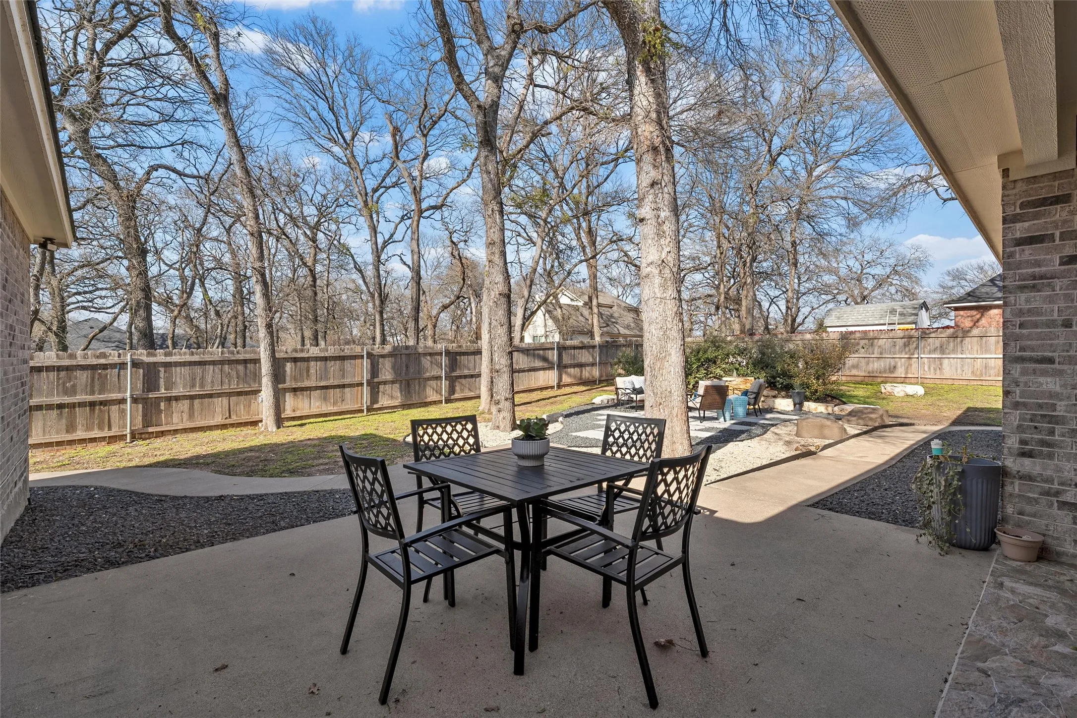 Private backyard retreat with expanded concrete patio, outdoor seating area, natural limestone water fountain feature, mature shade trees, and full wood privacy fence — outdoor living at its best at 117 Lost Oaks Drive, Waco TX 76705.