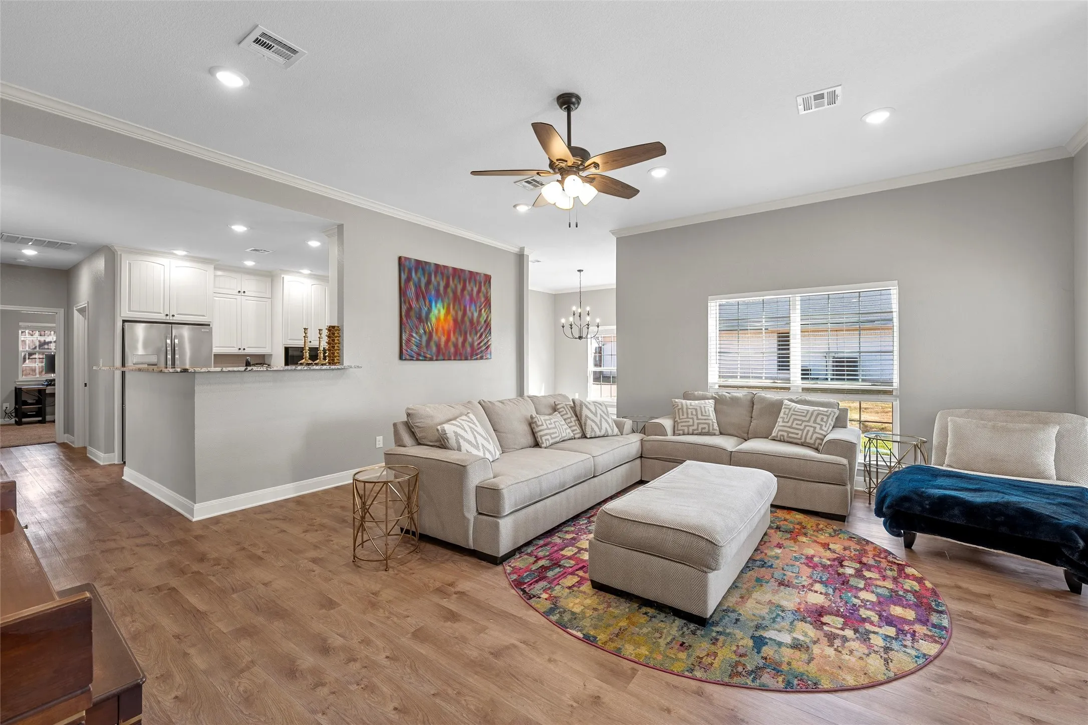Open-concept living room with crown molding, recessed lighting, ceiling fan, and wood-look luxury vinyl plank floors that flow seamlessly into the kitchen — perfect for entertaining at 117 Lost Oaks Drive, Waco TX.