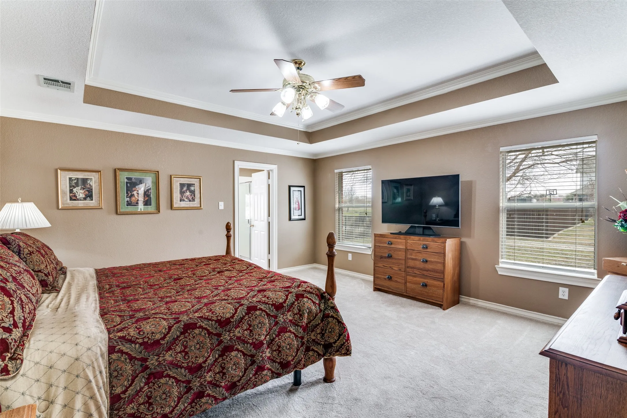 Bedroom featuring crown molding, light carpet, a tray ceiling, and ceiling fan
