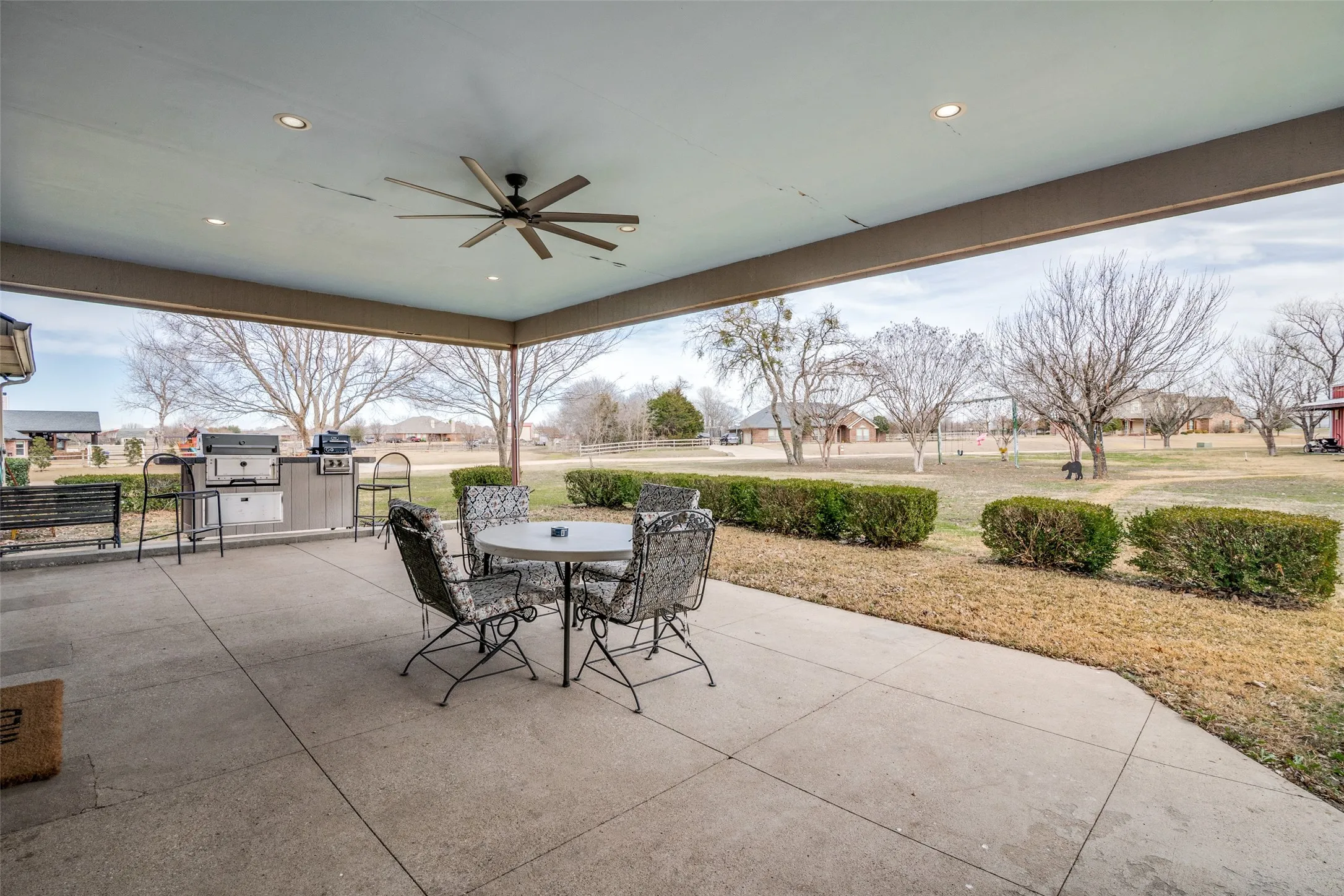 View of patio with outdoor dining area, ceiling fan, grilling area, and a residential view