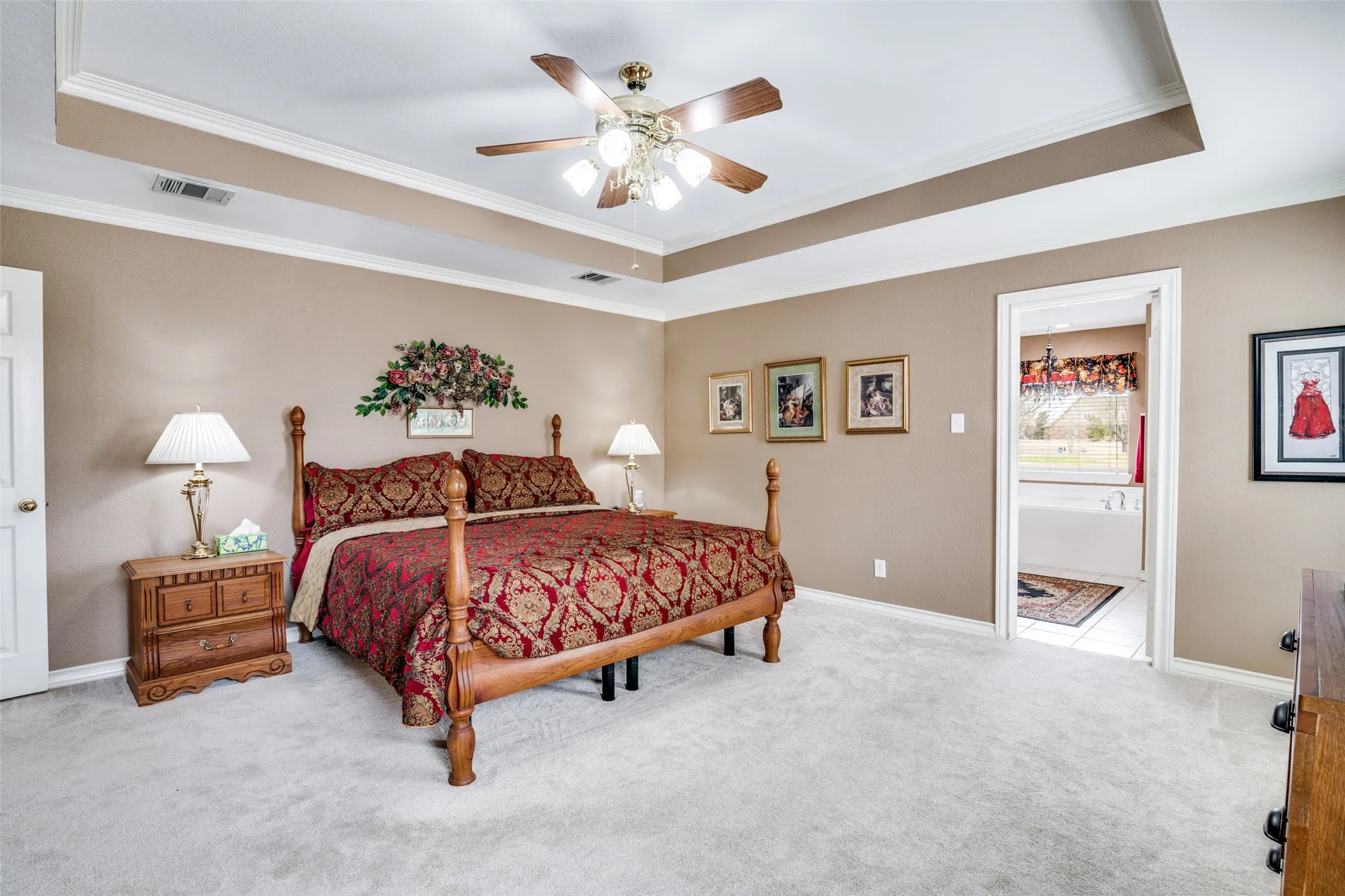Carpeted bedroom featuring a tray ceiling, ornamental molding, and a ceiling fan