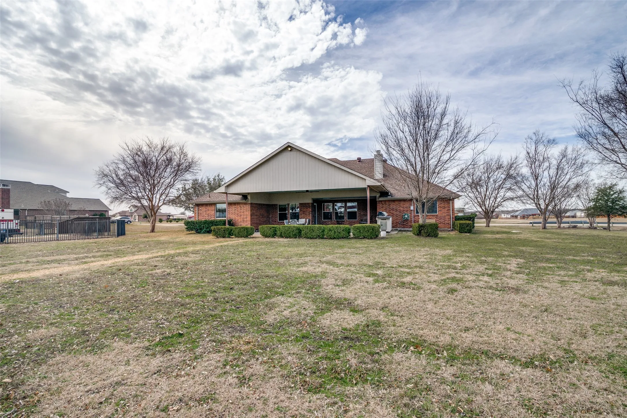View of rear of property with brick siding, a chimney, and a patio