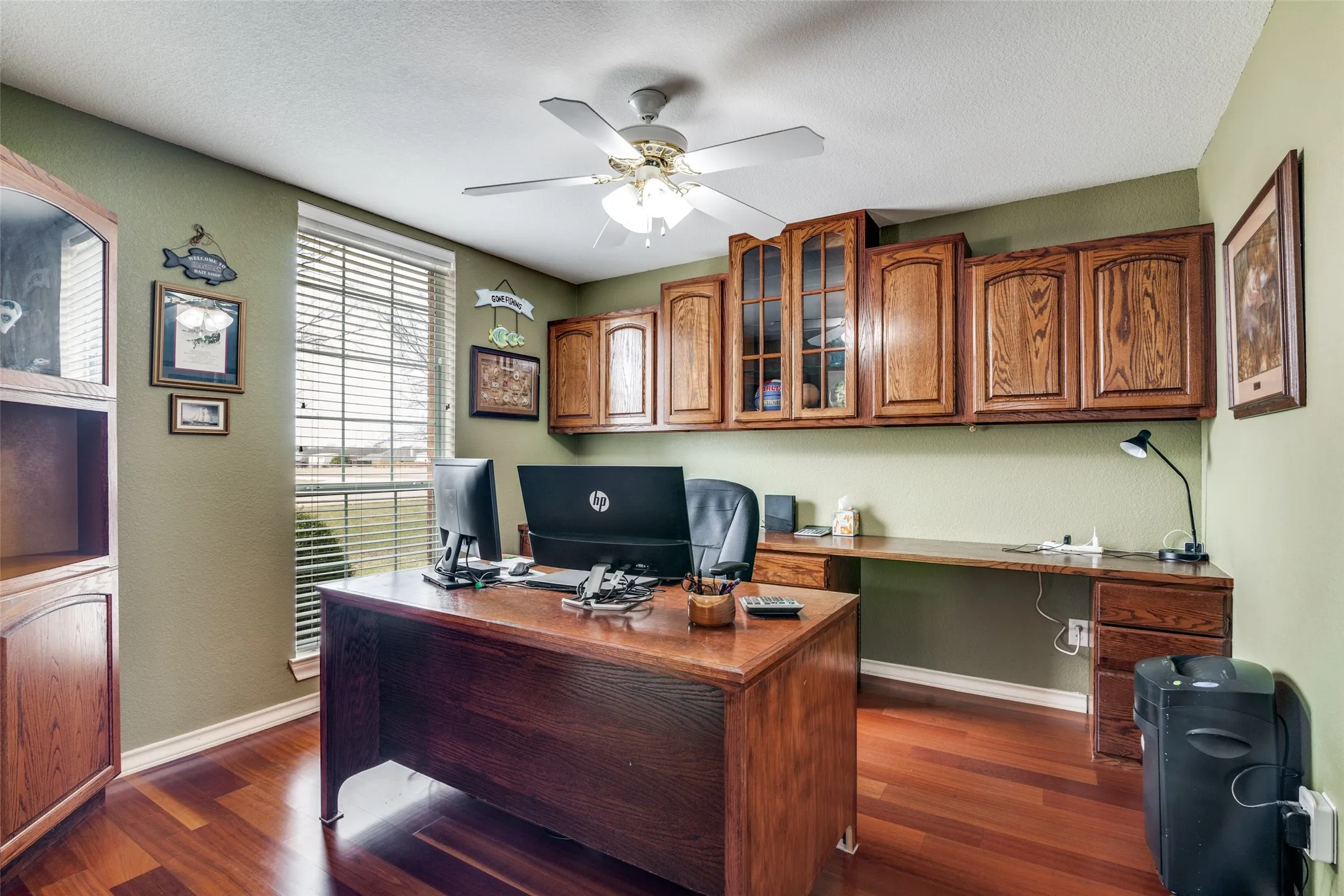 Office area with built in study area, a ceiling fan, and dark wood-type flooring