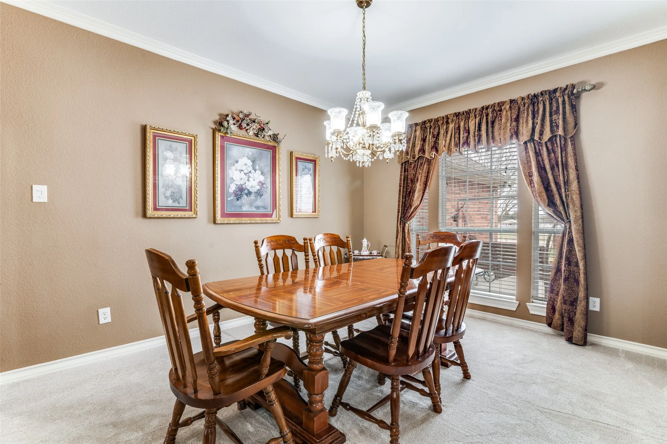 Dining room with light colored carpet, hanging lights, and crown molding