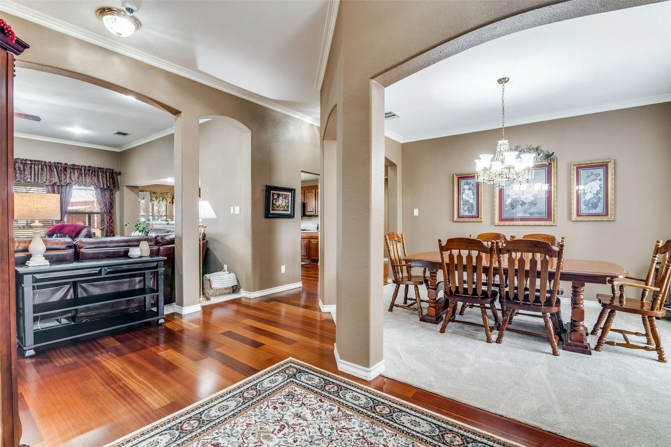 Dining room featuring arched walkways, crown molding, wood finished floors, and hanging lights