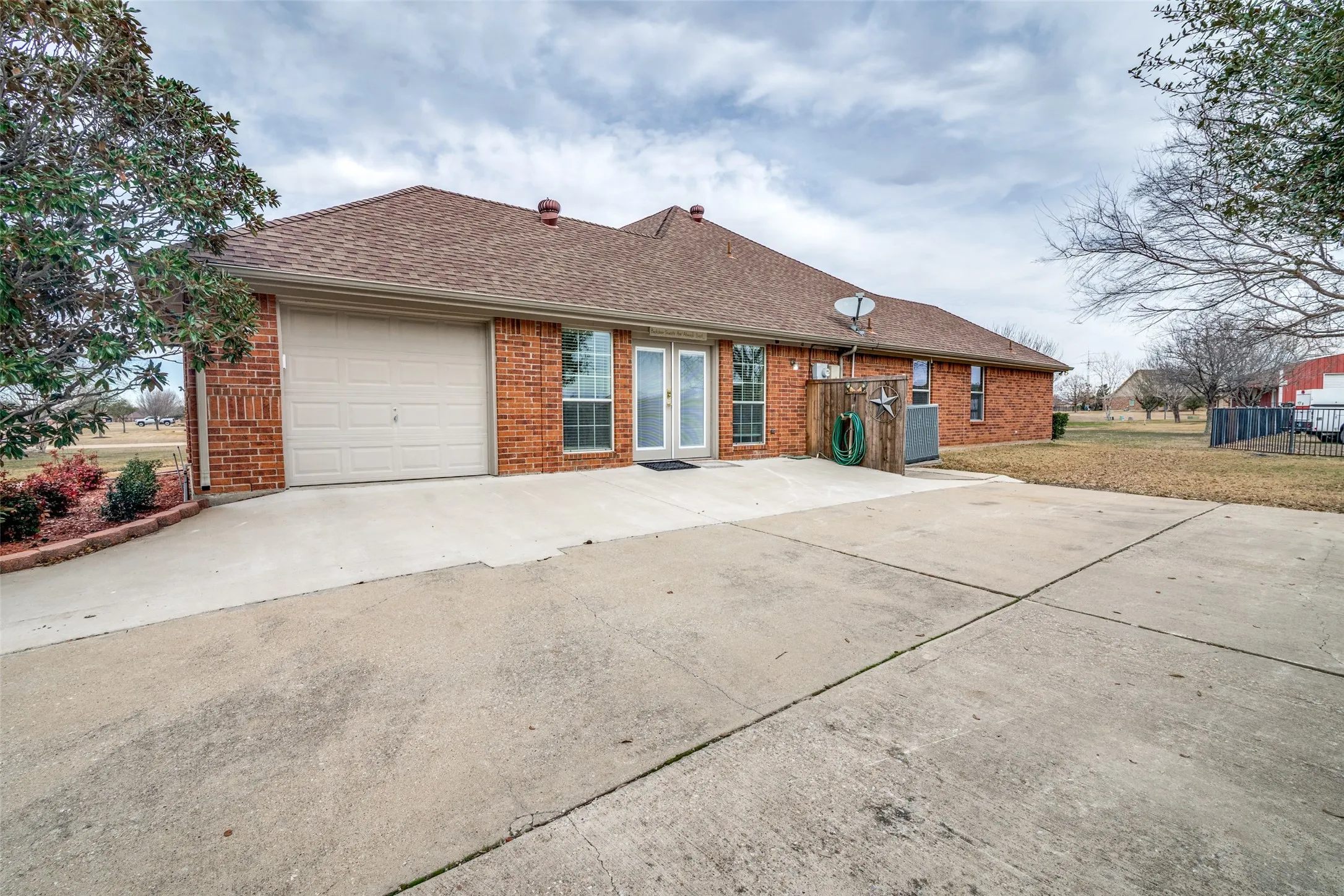Ranch-style home with a shingled roof, brick siding, concrete driveway, and a garage