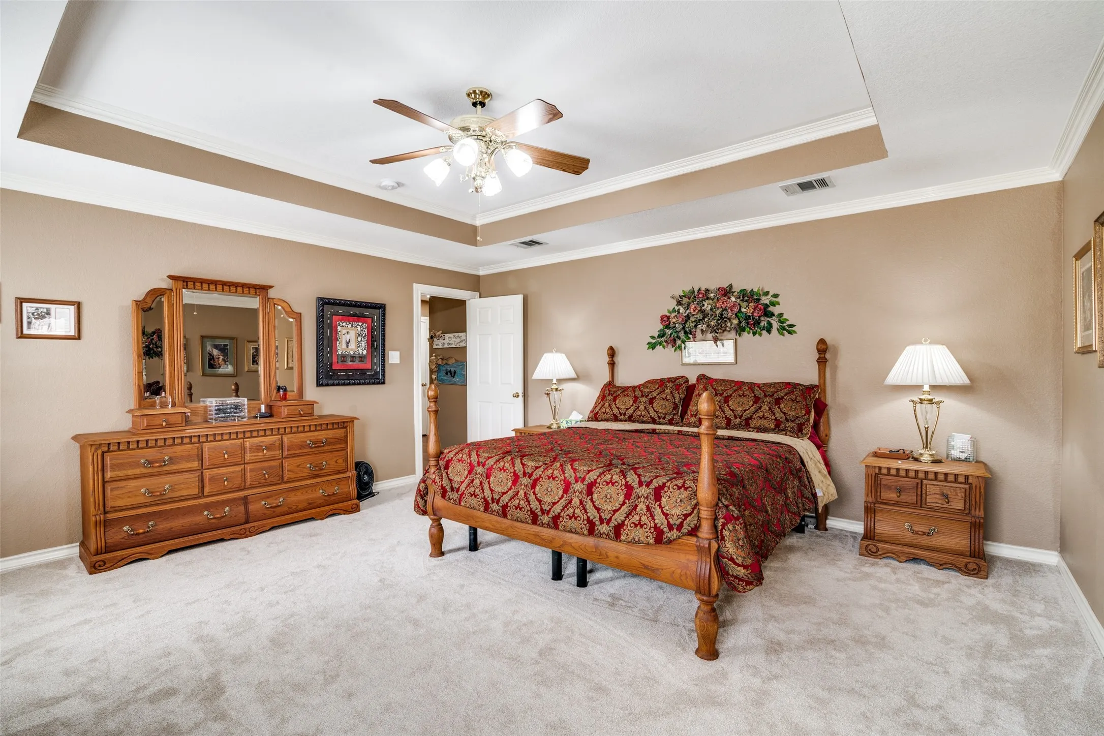 Bedroom featuring crown molding, a tray ceiling, carpet floors, and a ceiling fan