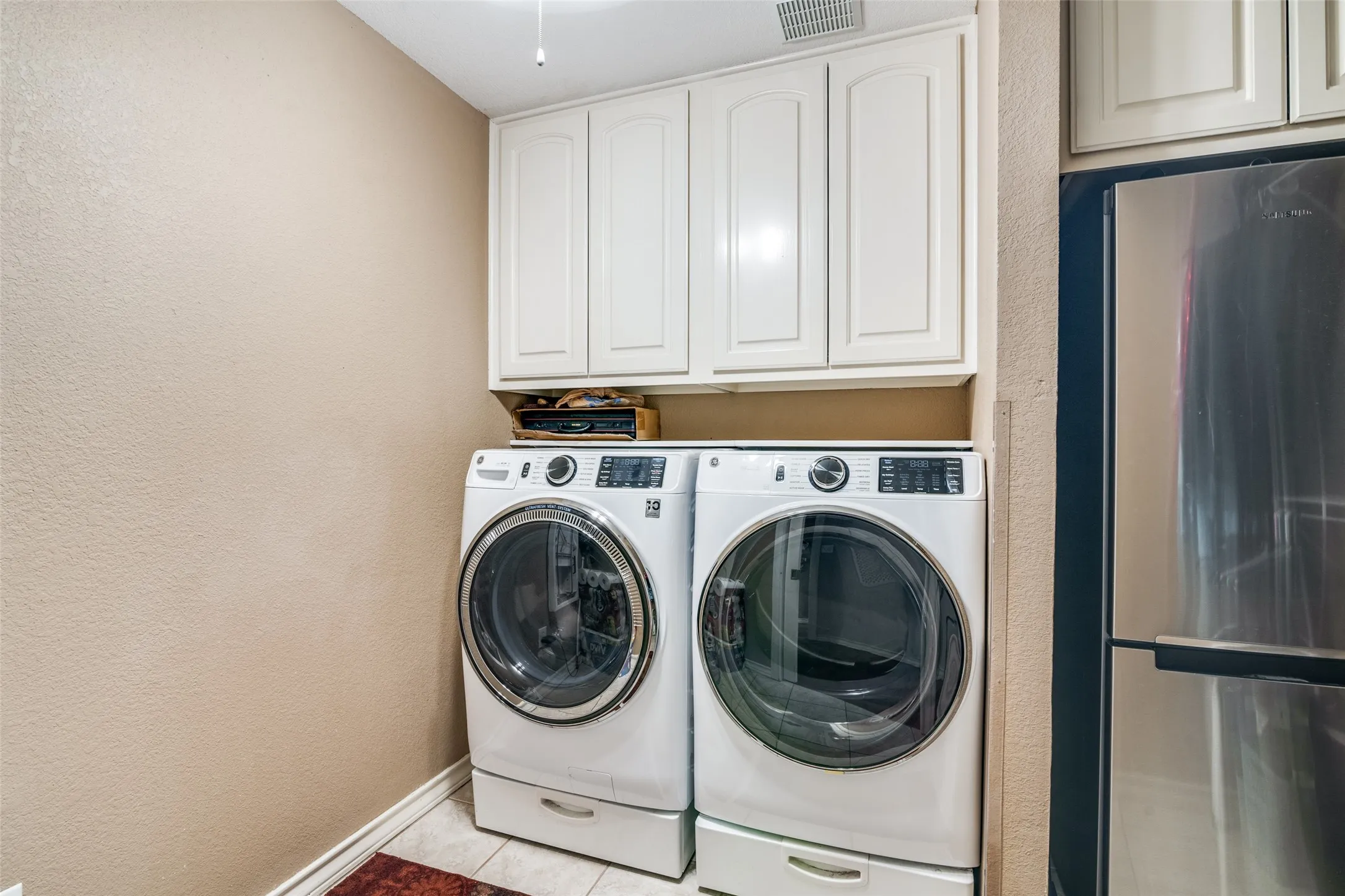 Laundry room featuring a textured wall, washing machine and dryer, and cabinet space